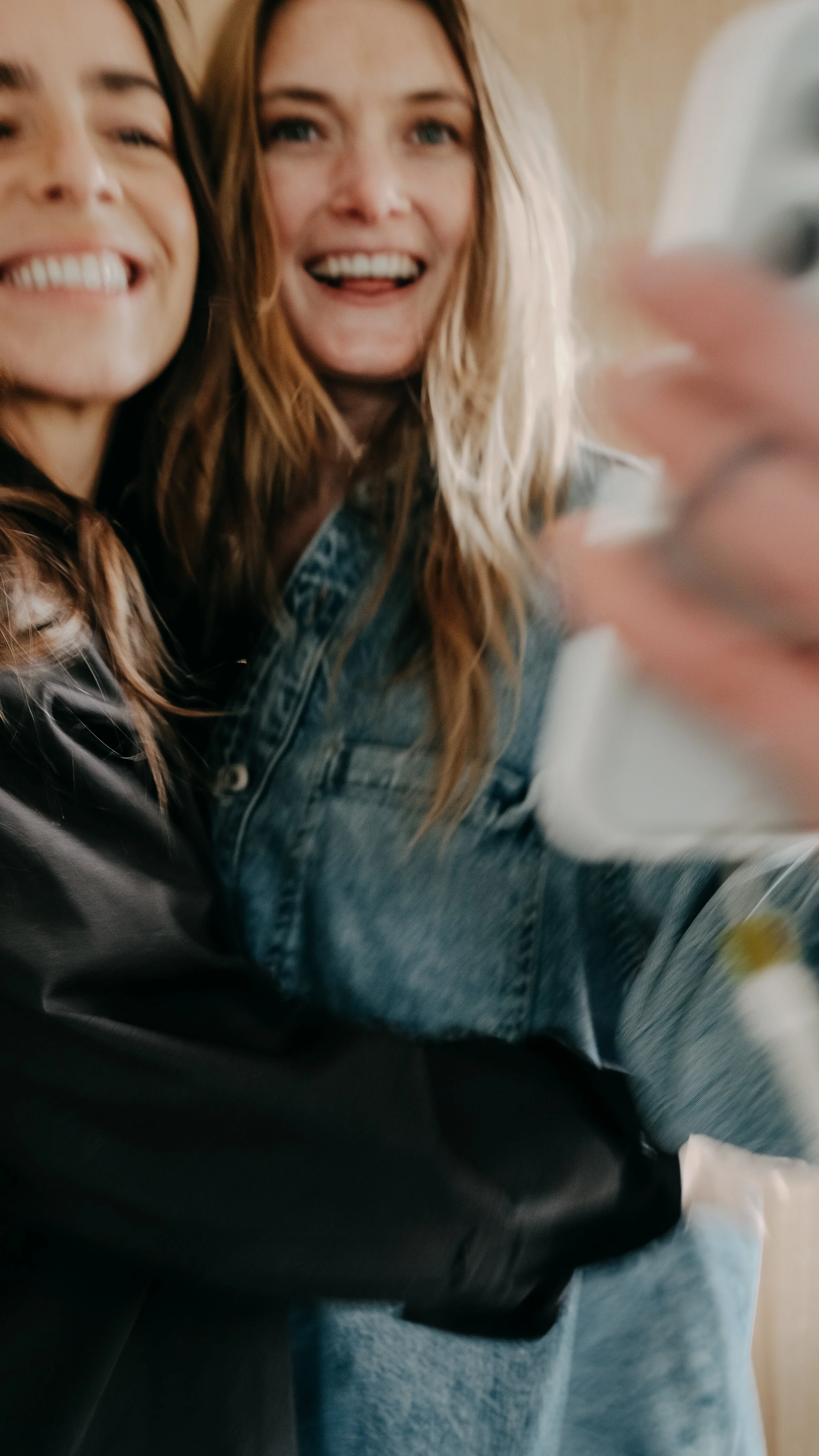 Two women smiling and taking a selfie together, with one holding a smartphone.