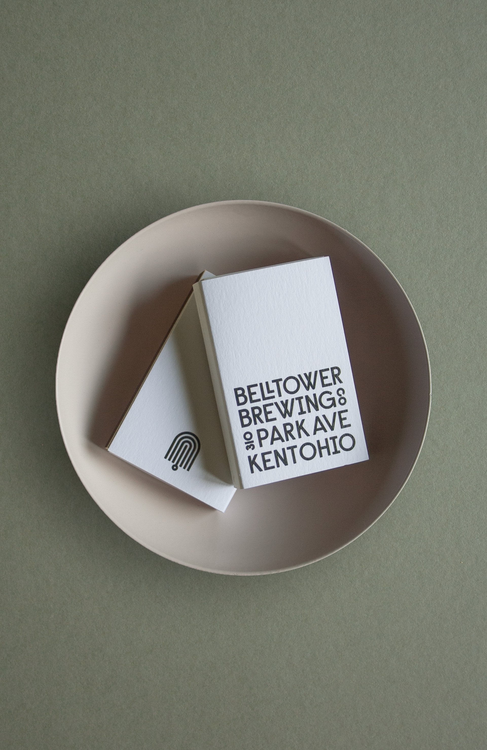 A white ceramic bowl containing matchbooks for BellTower Brewing.