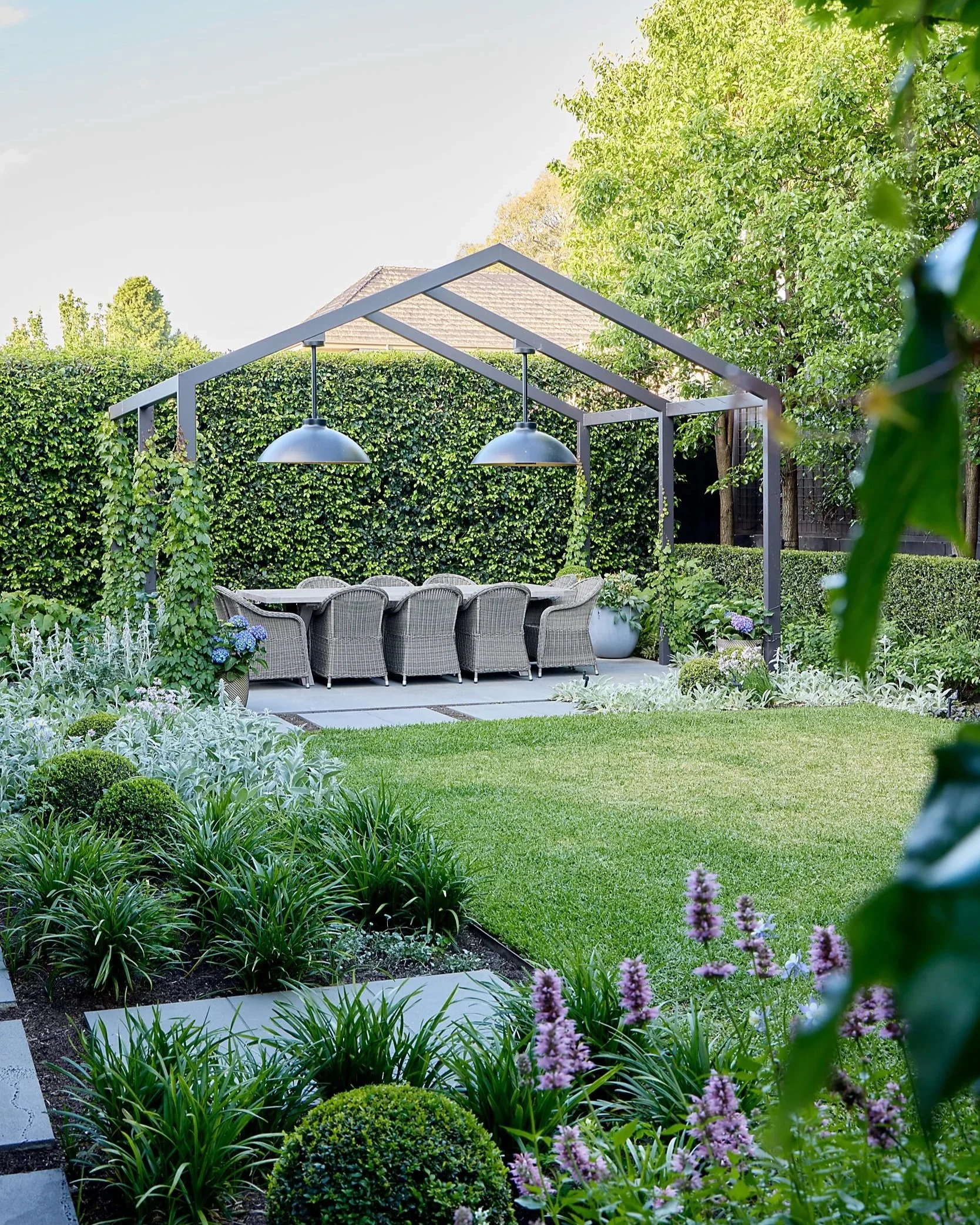 Image of back garden with lawn, outdoor table, and garden beds
