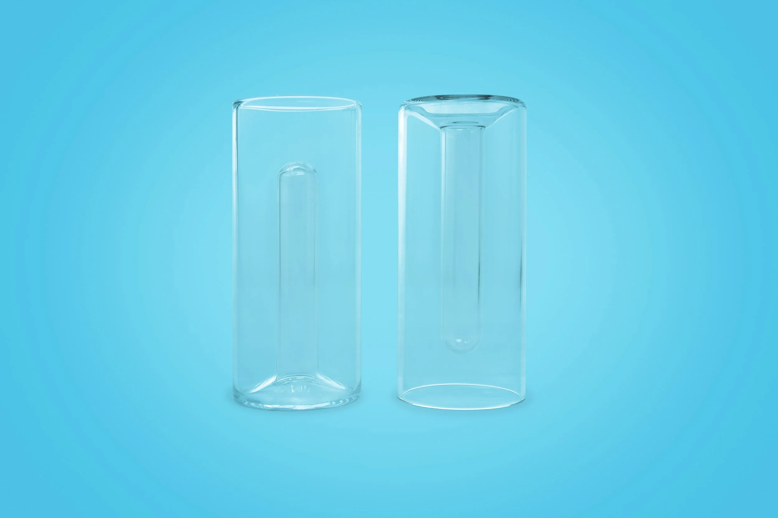 Two clear glass test tubes, one behind the other, against a blue background.