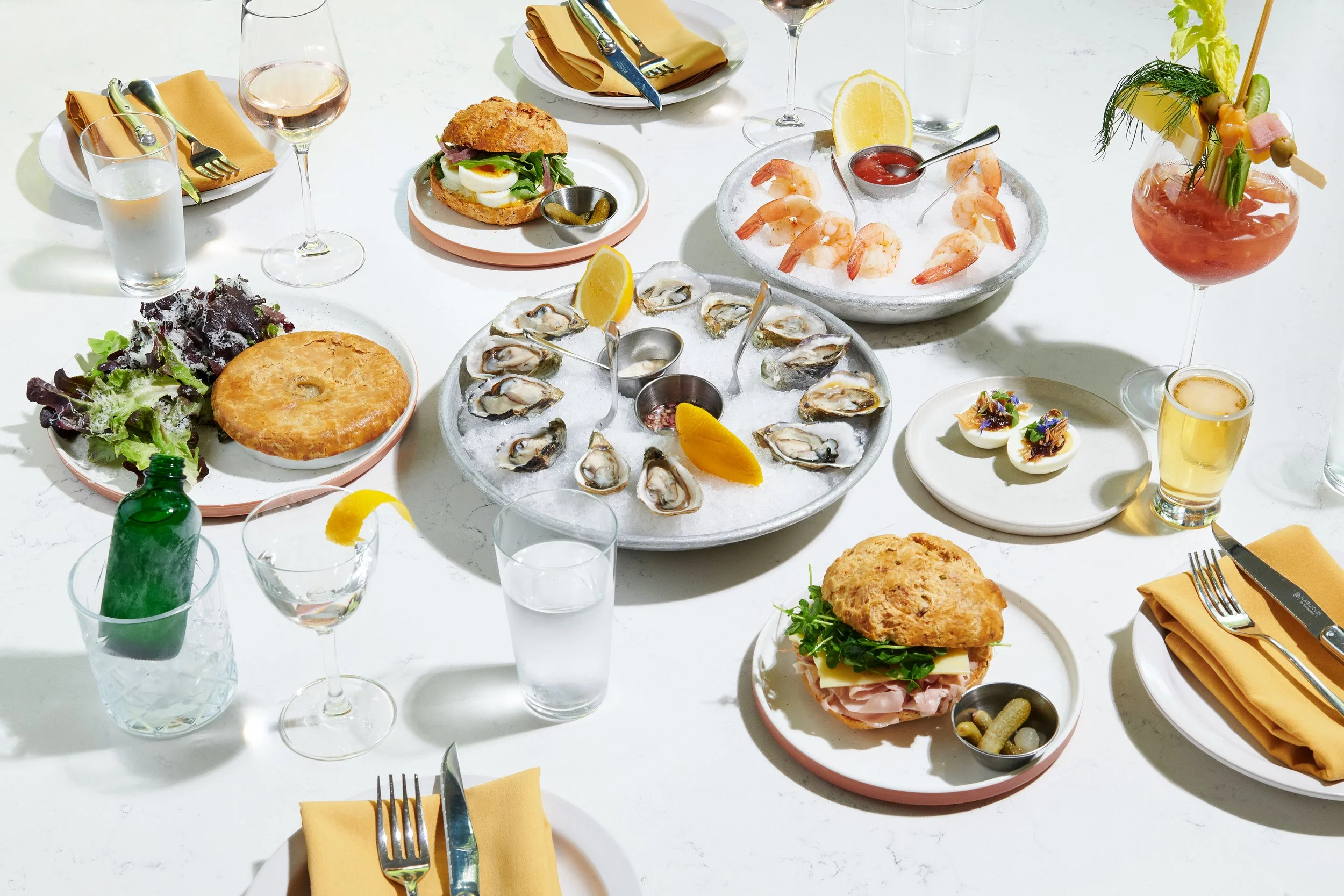 A table set with seafood, sandwiches, salads, and drinks for a meal or party.