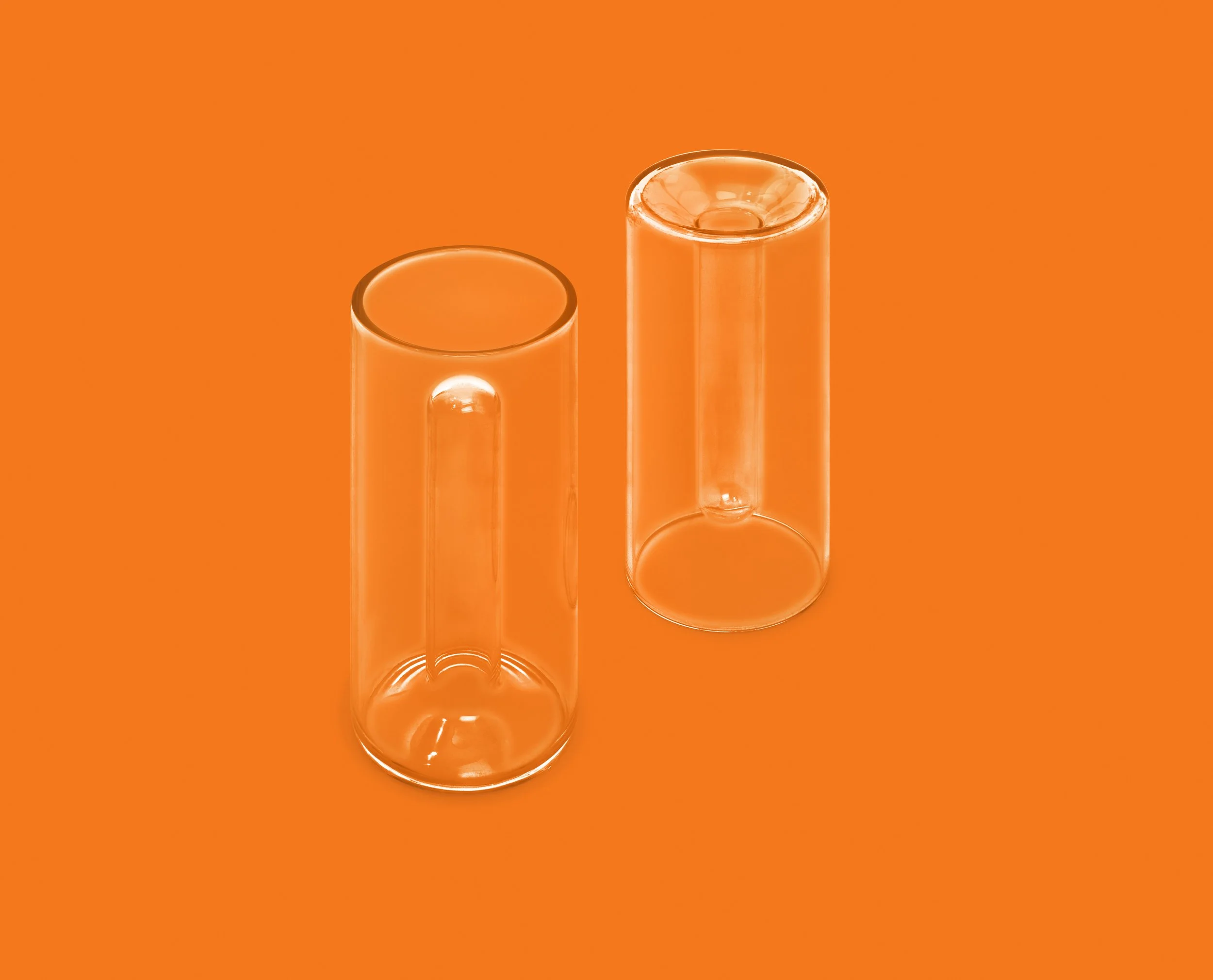 Two empty transparent glass tumblers placed on an orange surface.