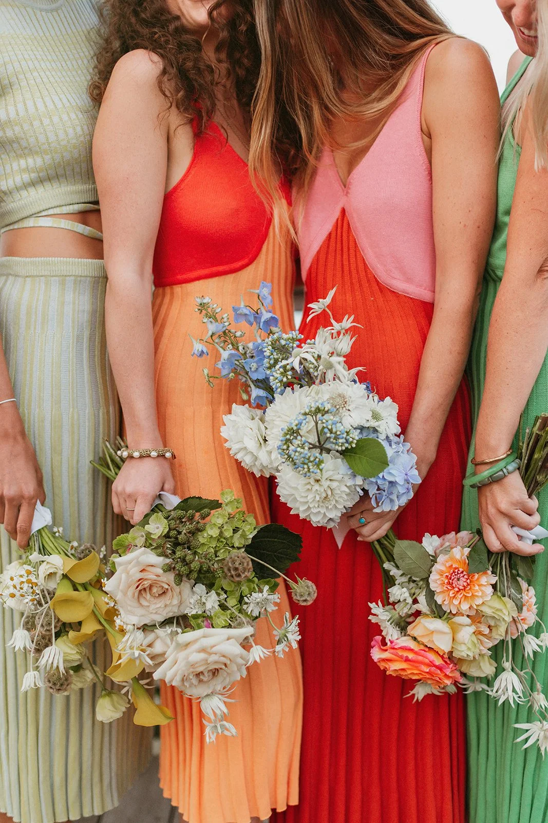 Women dressed in colorful dresses holding bouquets of flowers at a celebration or gathering