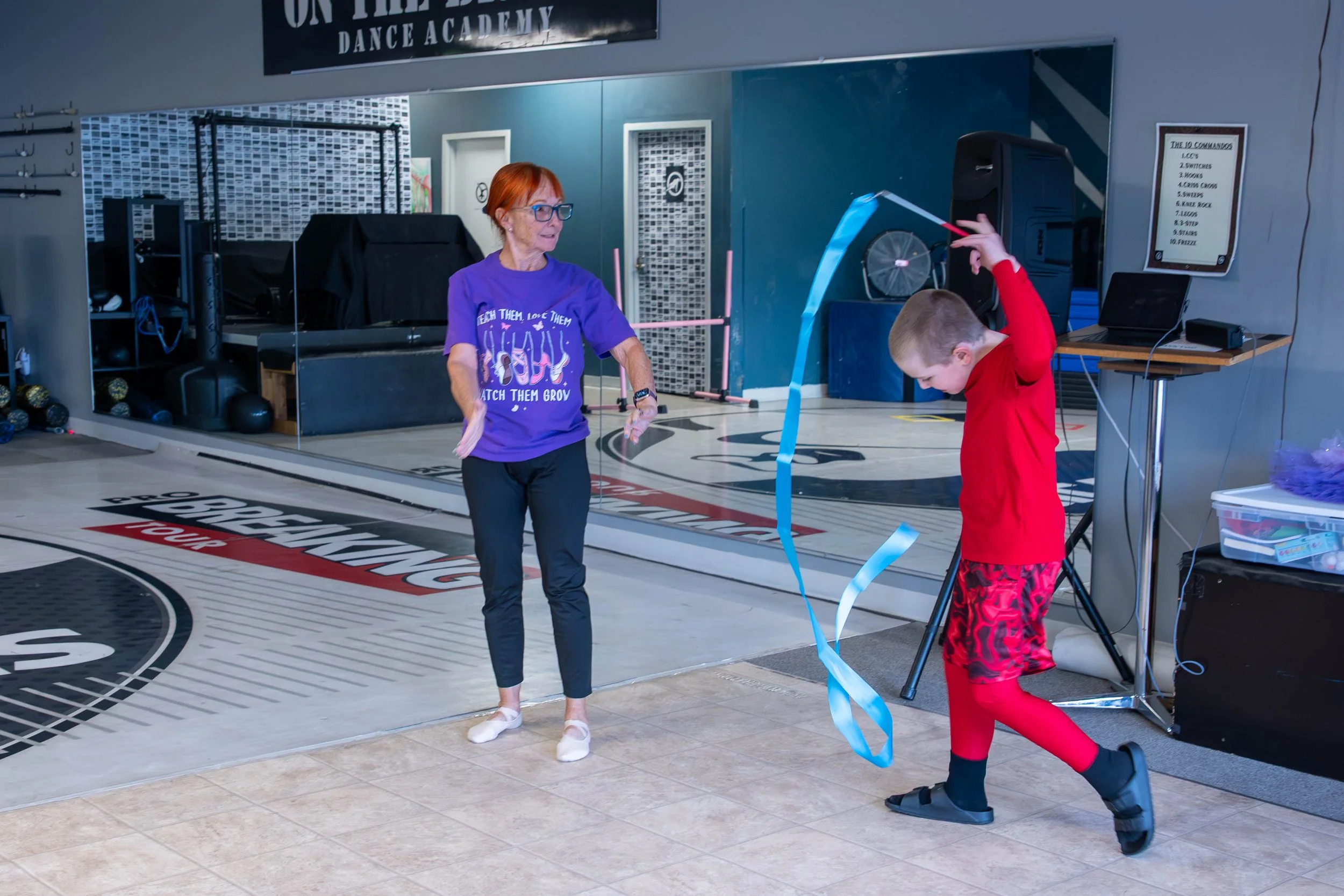 A boy with a ribbon working with a dance teacher