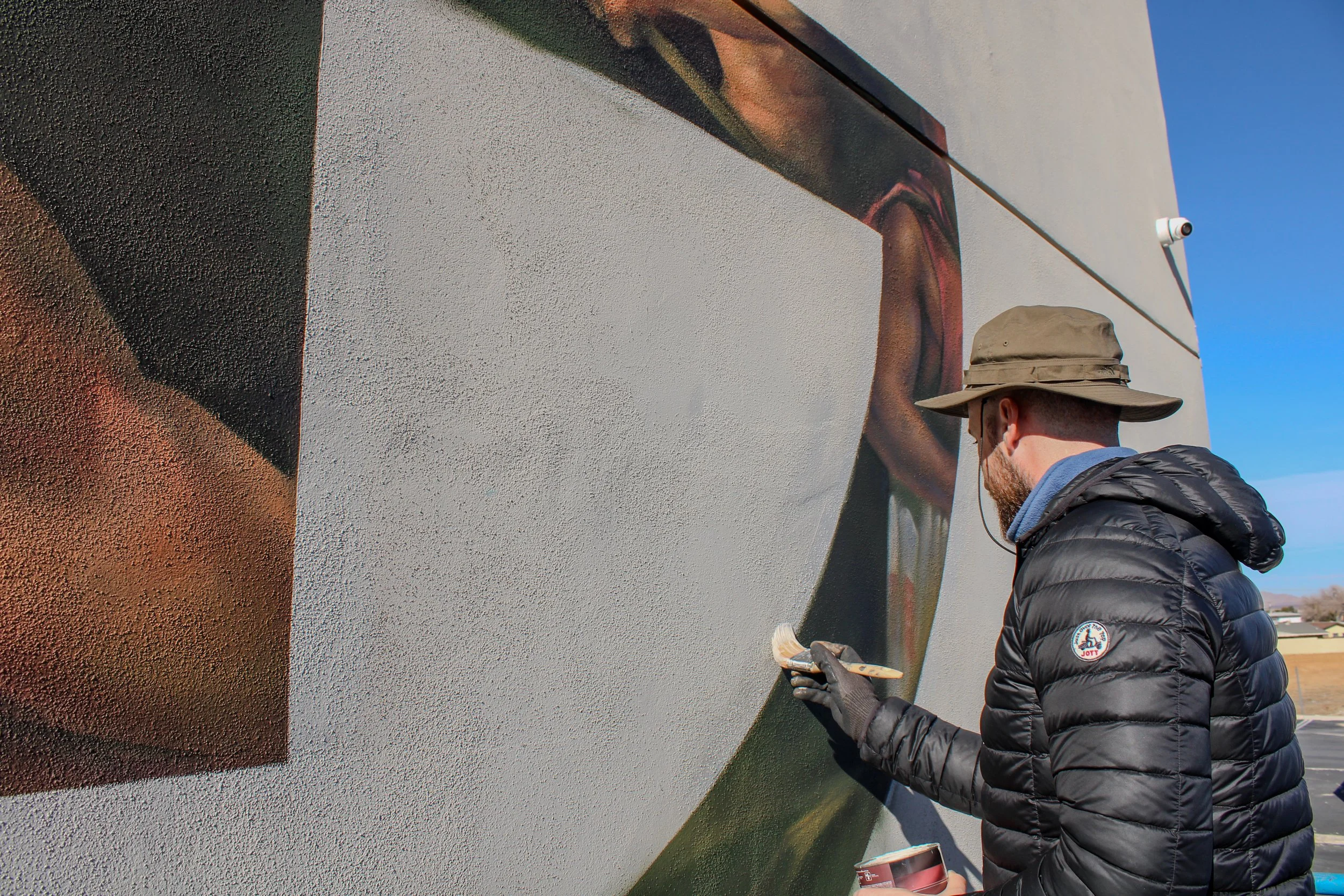 Pezer97 painting large-scale outdoor gym mural on exterior wall of The Gym Southern California