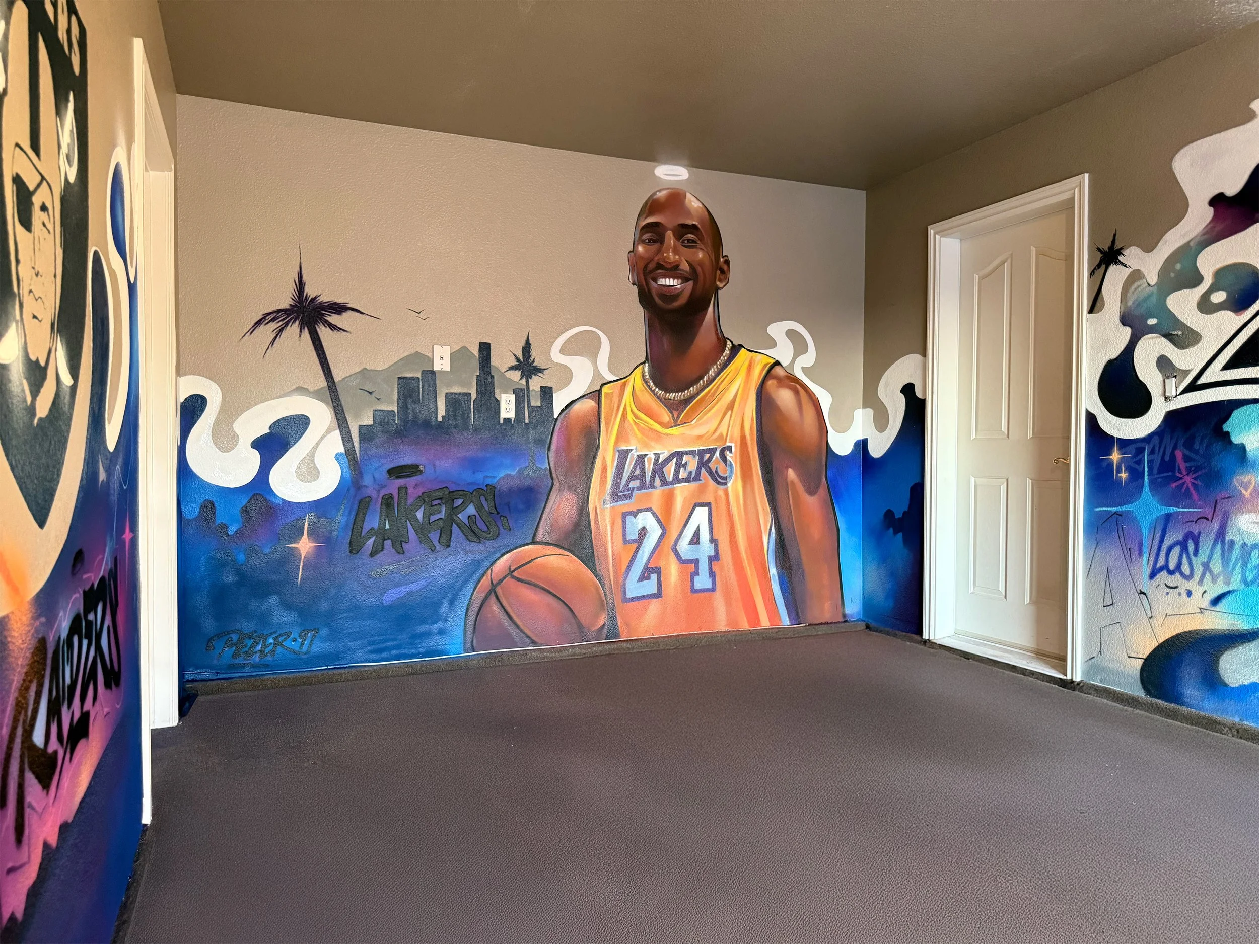 Murals of a basketball player in Los Angeles with city skyline, palm trees, and graffiti-style elements.