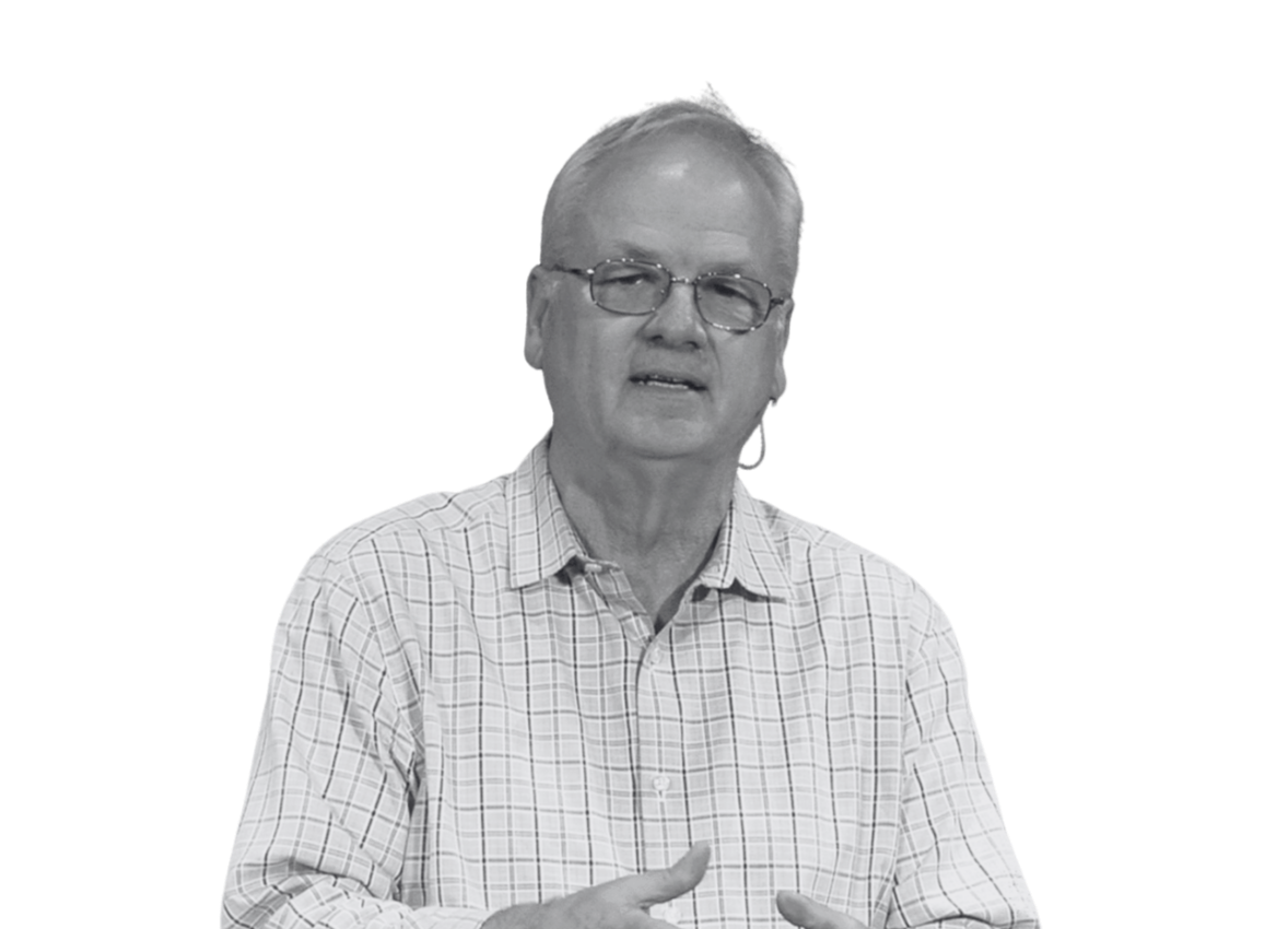 A middle-aged man with glasses and light-colored hair speaking, wearing a checkered shirt.
