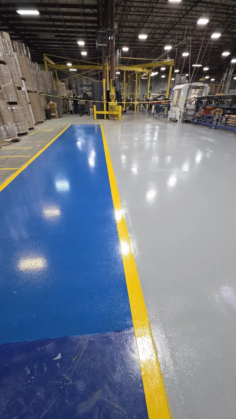 Industrial plant floor coated in blue and gray epoxy with yellow safety lines