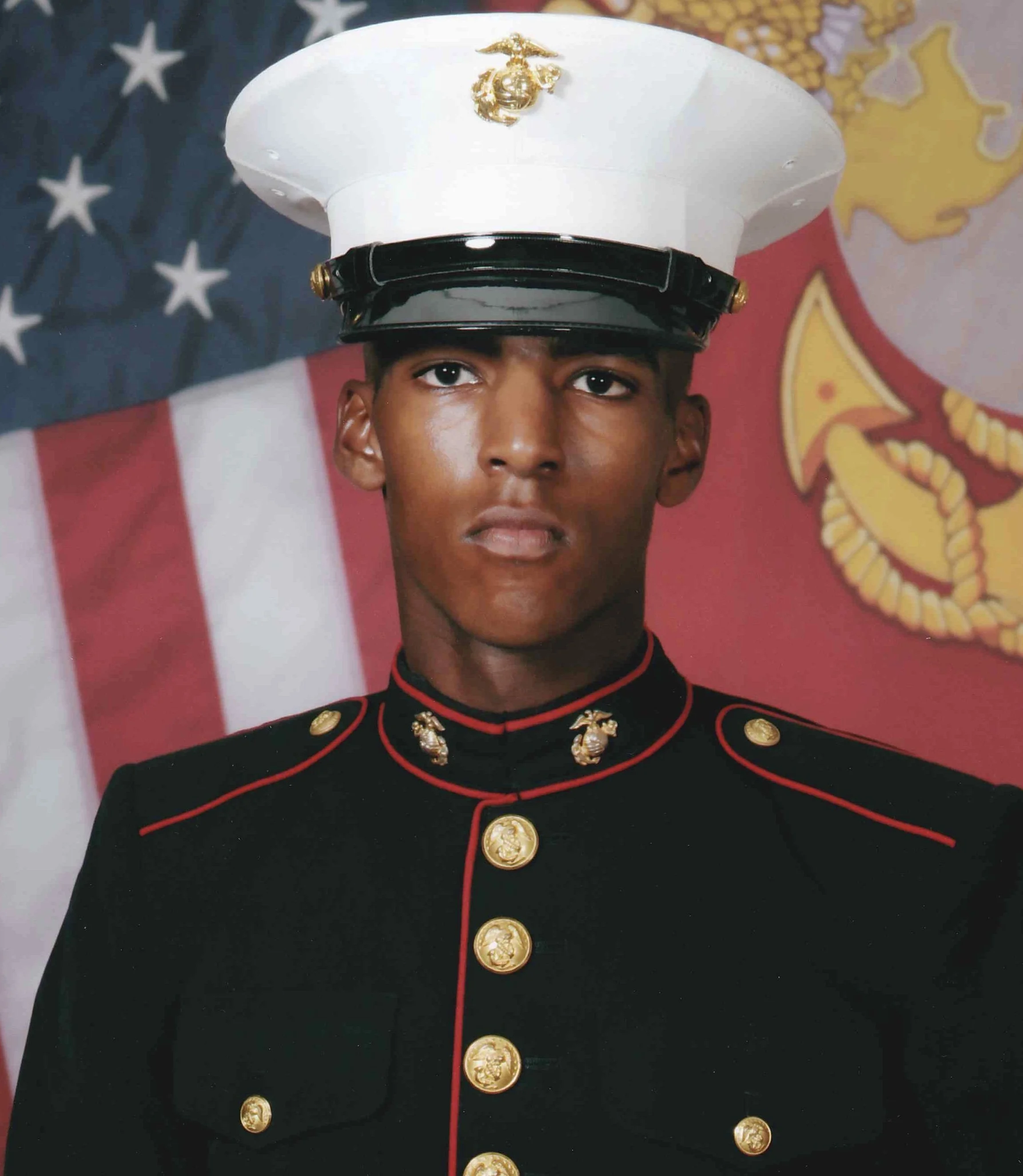 Bryan C. Nelson, a United States Marine in dress uniform in front of American and Marine Corps flags.