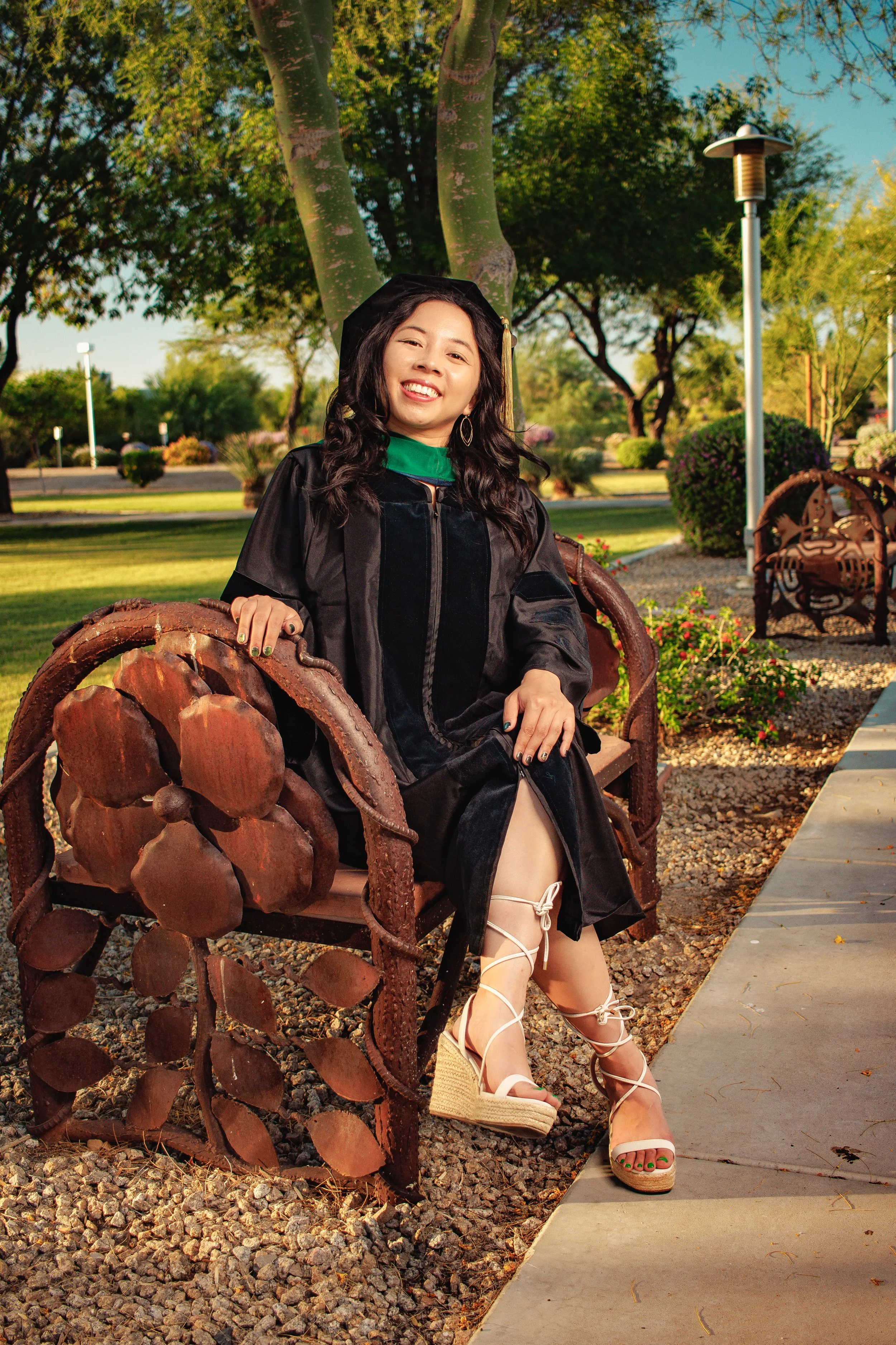 A young lady in graduation attire sitting on a bench on the Midwestern University Campus located in Glendale, Arizona.