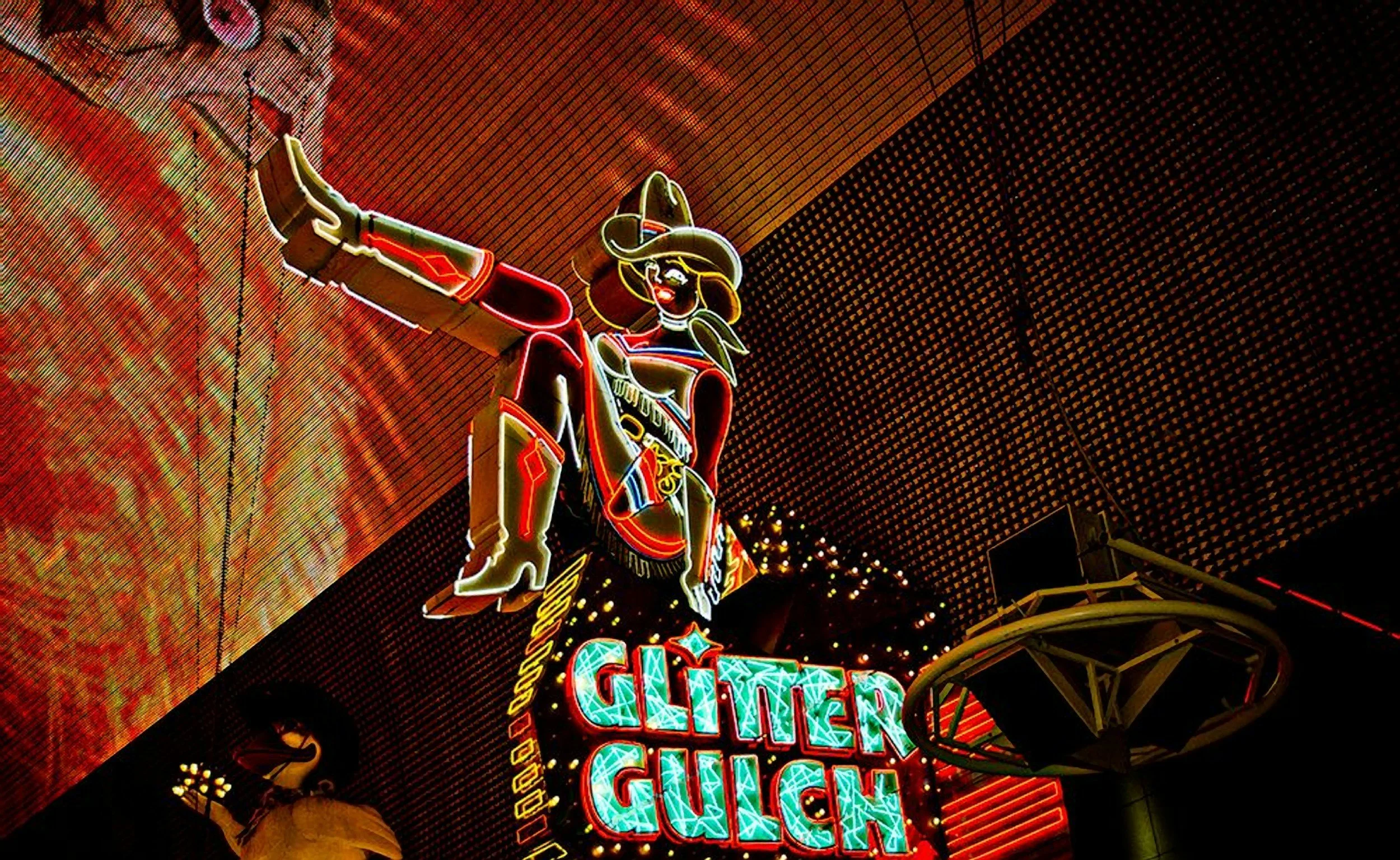 Neon sign of a cartoon cowboy girl wearing a hat, sitting on a barrel, with the word 'GIRL' illuminated below.