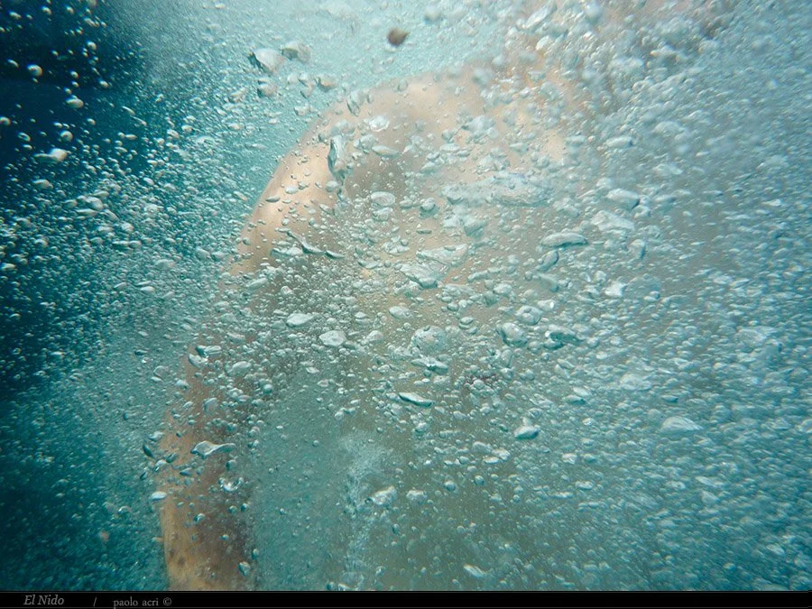 A person swimming underwater with bubbles surrounding them.