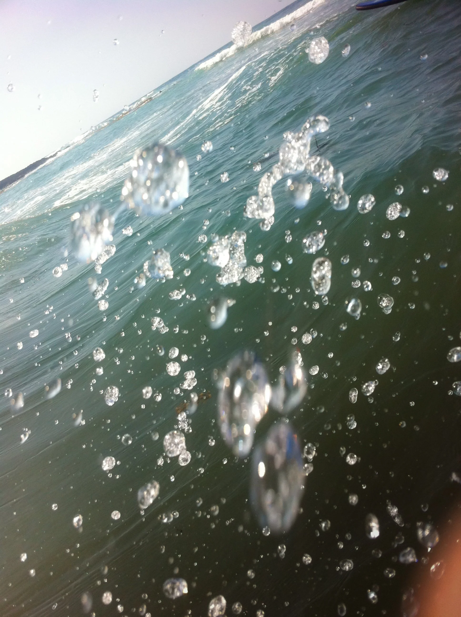 Close-up of an ocean wave with water droplets and bubbles in mid-air.