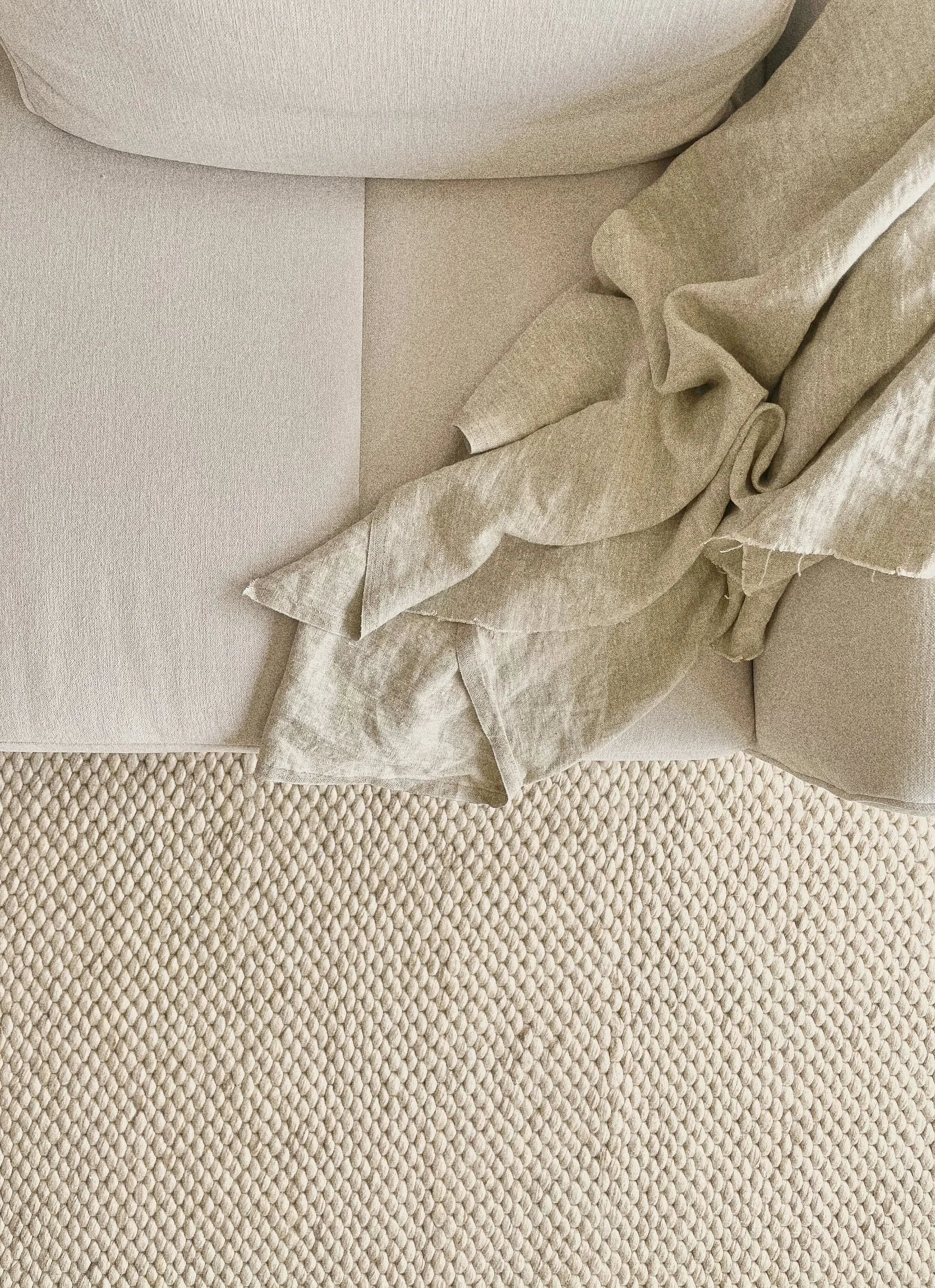 Close-up of a beige fabric sofa with a textured cushion and a linen throw draped over the corner.“Residential interior design project in Scotland by [Studio Name], working across Glasgow, Edinburgh, Dundee and the Highlands.”

“Contemporary Scottish 