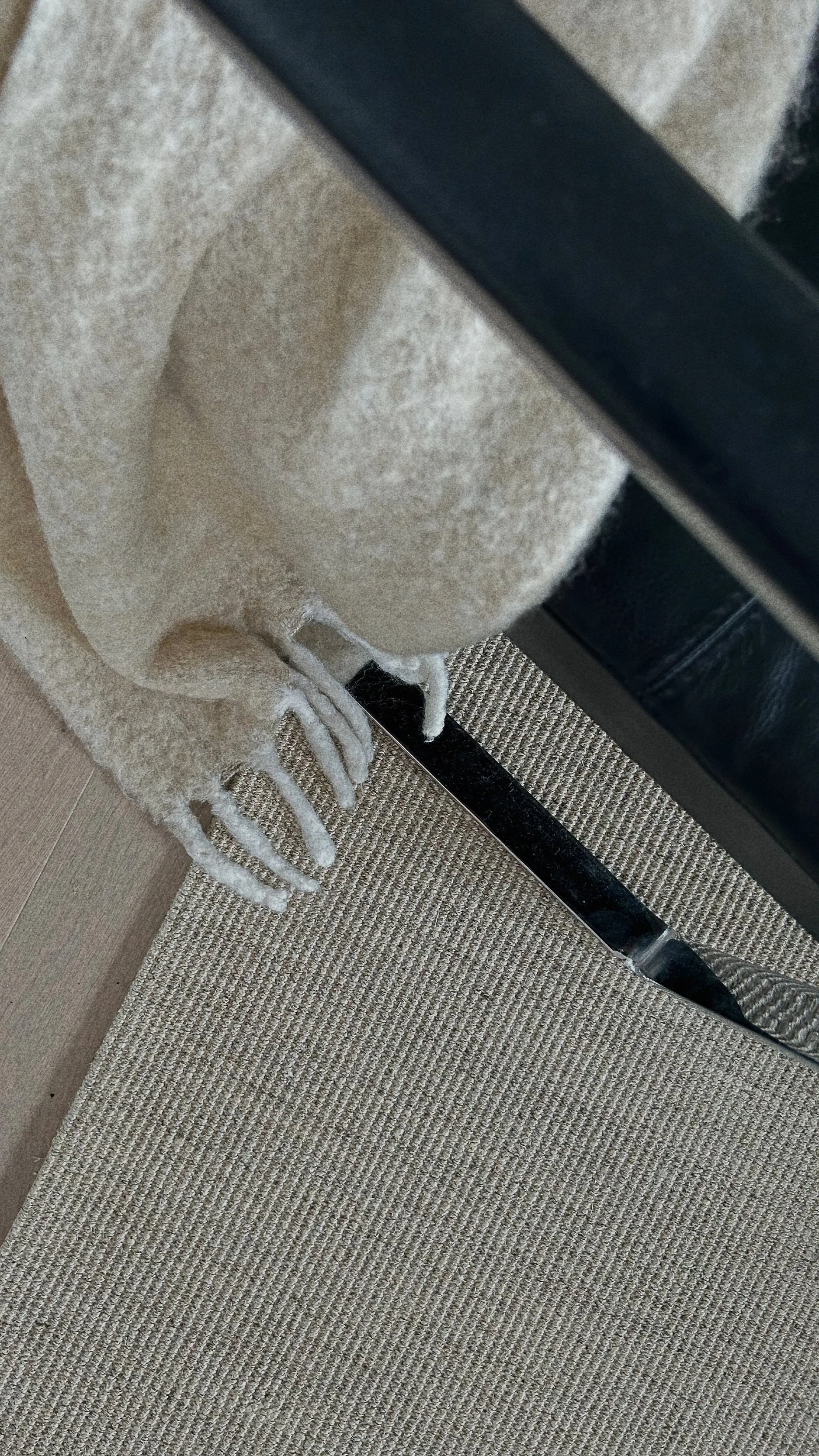Close-up of a person's foot wearing a fluffy beige sock with white laces, next to a black metal leg of a piece of furniture on a beige textured carpet.Residential interior design project in Scotland - Interior Designer Scotland - Interiors 