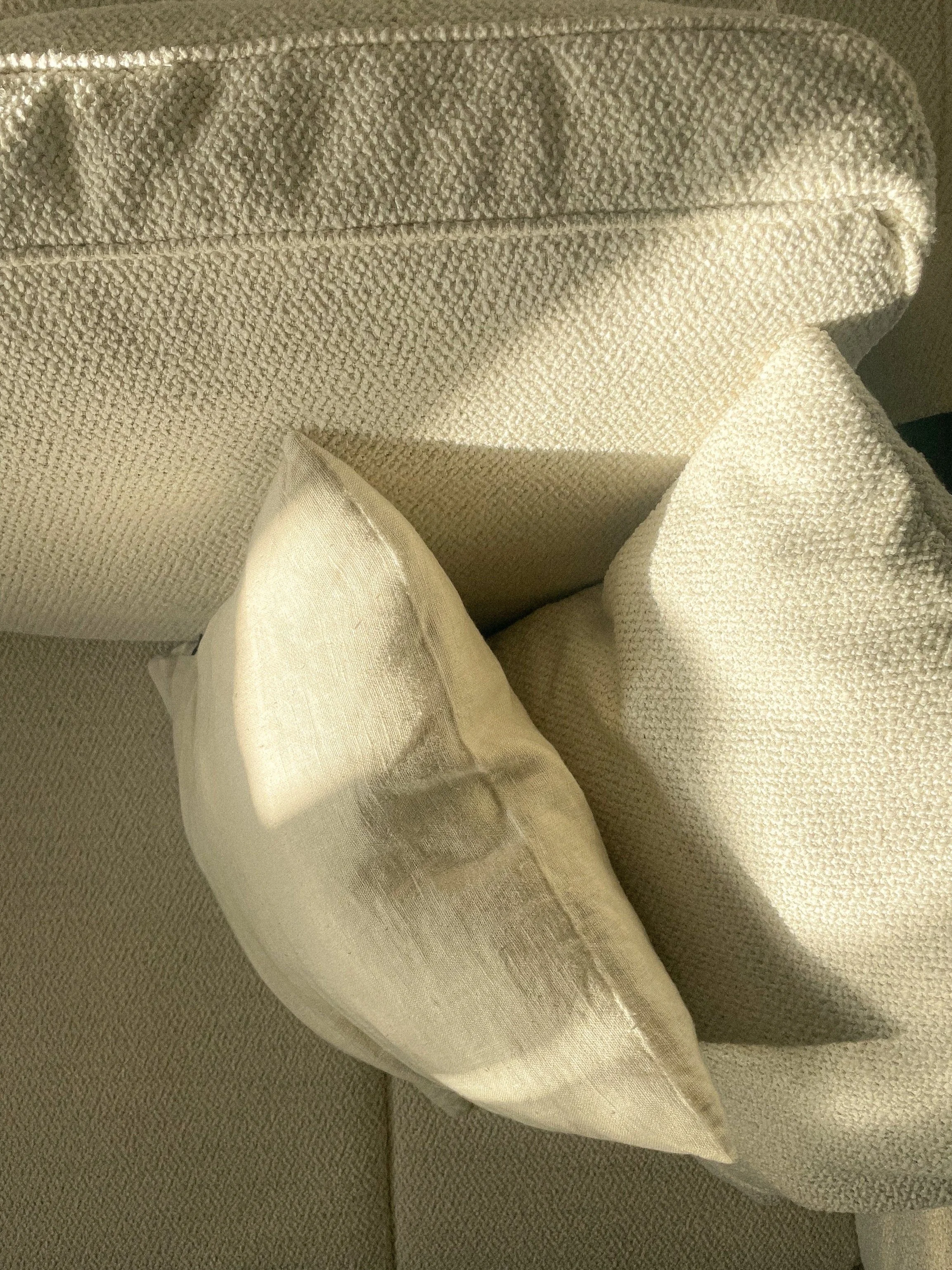 Close-up of a beige upholstered chair with a cream-colored pillow resting against the armrest, bathed in natural sunlight.“Residential interior design project in Scotland by [Studio Name], working across Glasgow, Edinburgh, Dundee and the Highlands.”