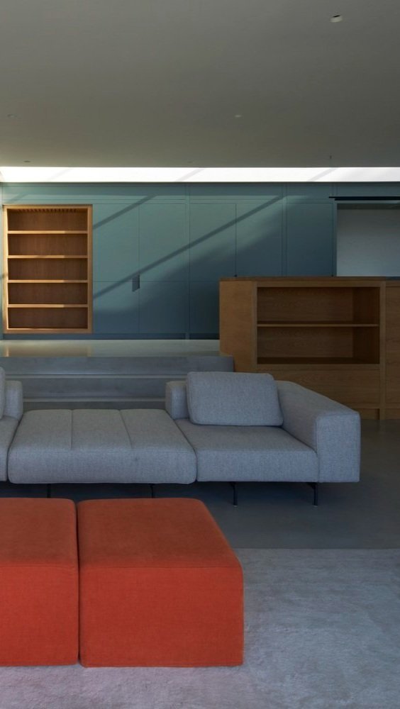 Modern interior with gray sofa, orange ottoman, blue wall, wooden shelving unit, and a wall-mounted wooden cabinet.“Residential interior design project in Scotland by [Studio Name], working across Glasgow, Edinburgh, Dundee and the Highlands.”

“Cont