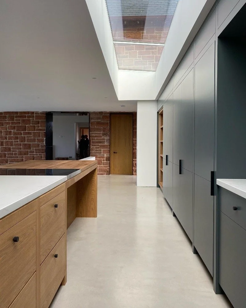Modern kitchen interior with wooden cabinets, gray cabinetry, a skylight ceiling, and a brick wall in the background.“Residential interior design project in Scotland by [Studio Name], working across Glasgow, Edinburgh, Dundee and the Highlands.”

“Co