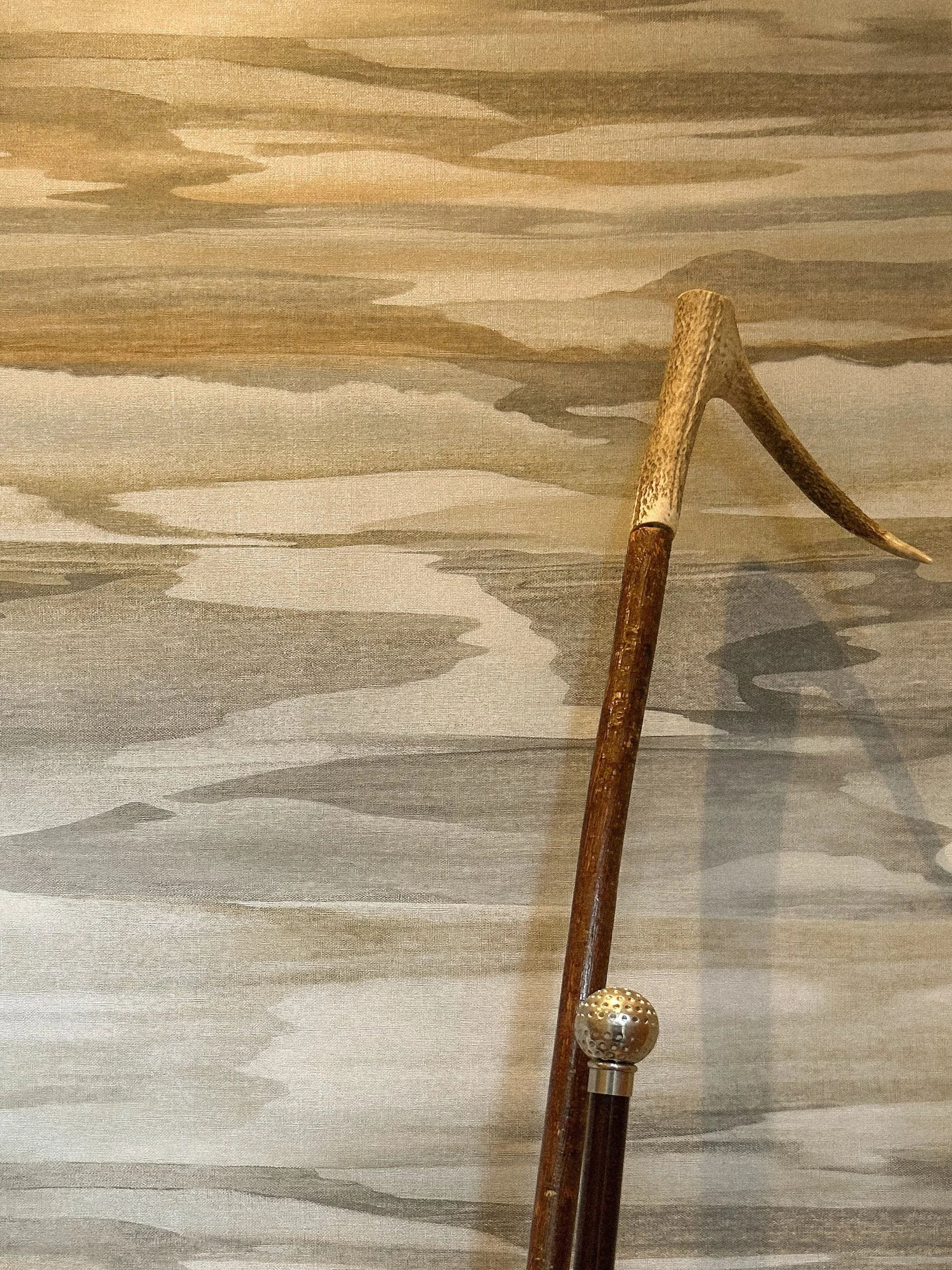 A vintage wooden walking cane with a metal ball handle, leaning against a textured wall with a painted landscape scene.“Residential interior design project in Scotland by [Studio Name], working across Glasgow, Edinburgh, Dundee and the Highlands.”

“