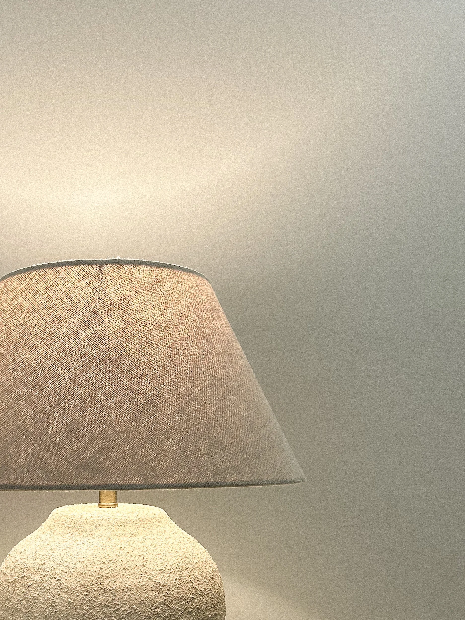 A table lamp with a textured, off-white base and a beige fabric lampshade against a plain beige wall.“Residential interior design project in Scotland by [Studio Name], working across Glasgow, Edinburgh, Dundee and the Highlands.”

“Contemporary Scott