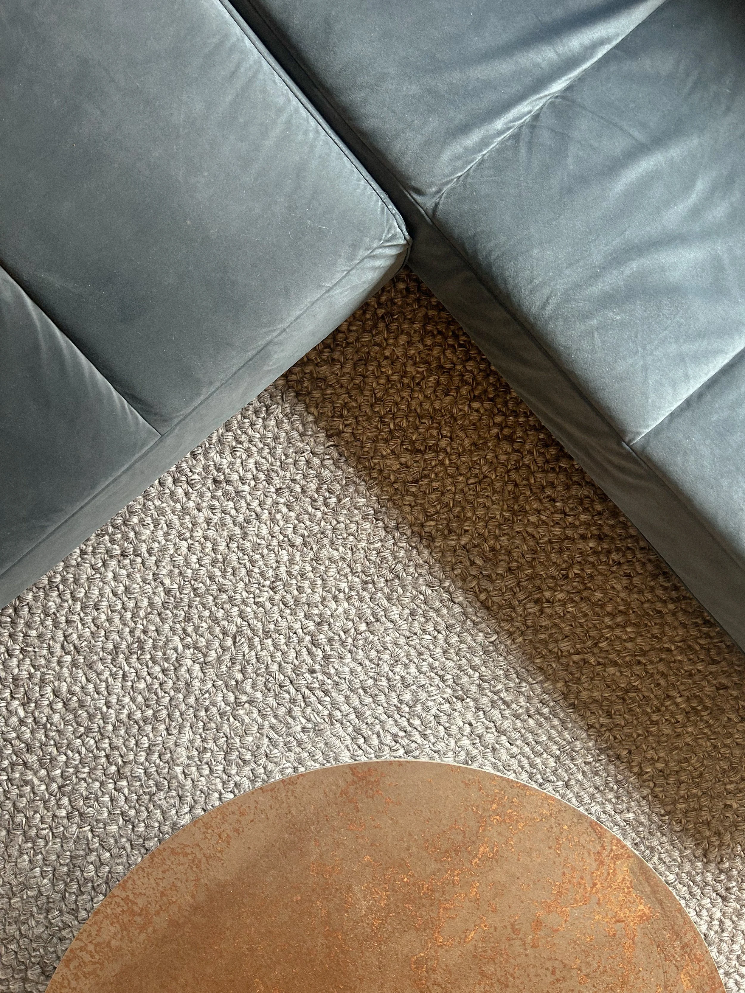 Close-up of a corner of a gray leather couch on a woven beige and brown rug with part of a rust-colored round table visible in the bottom of the image.Residential interior design project in Scotland - Interior Designer Scotland - Interiors 