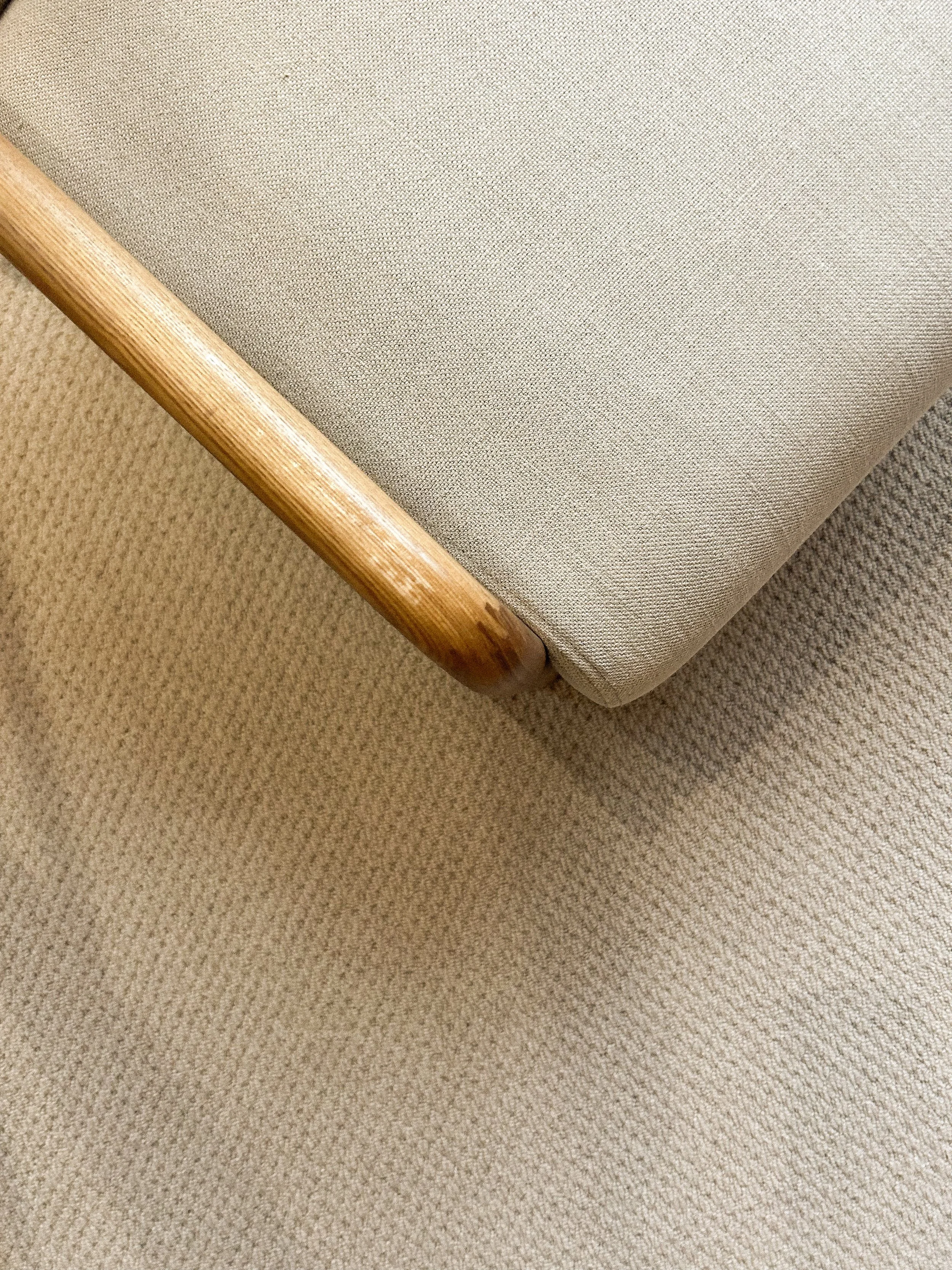 Close-up of a corner of a beige upholstered chair with a wooden armrest, resting on a beige textured carpet.“Residential interior design project in Scotland by [Studio Name], working across Glasgow, Edinburgh, Dundee and the Highlands.”

“Contemporar