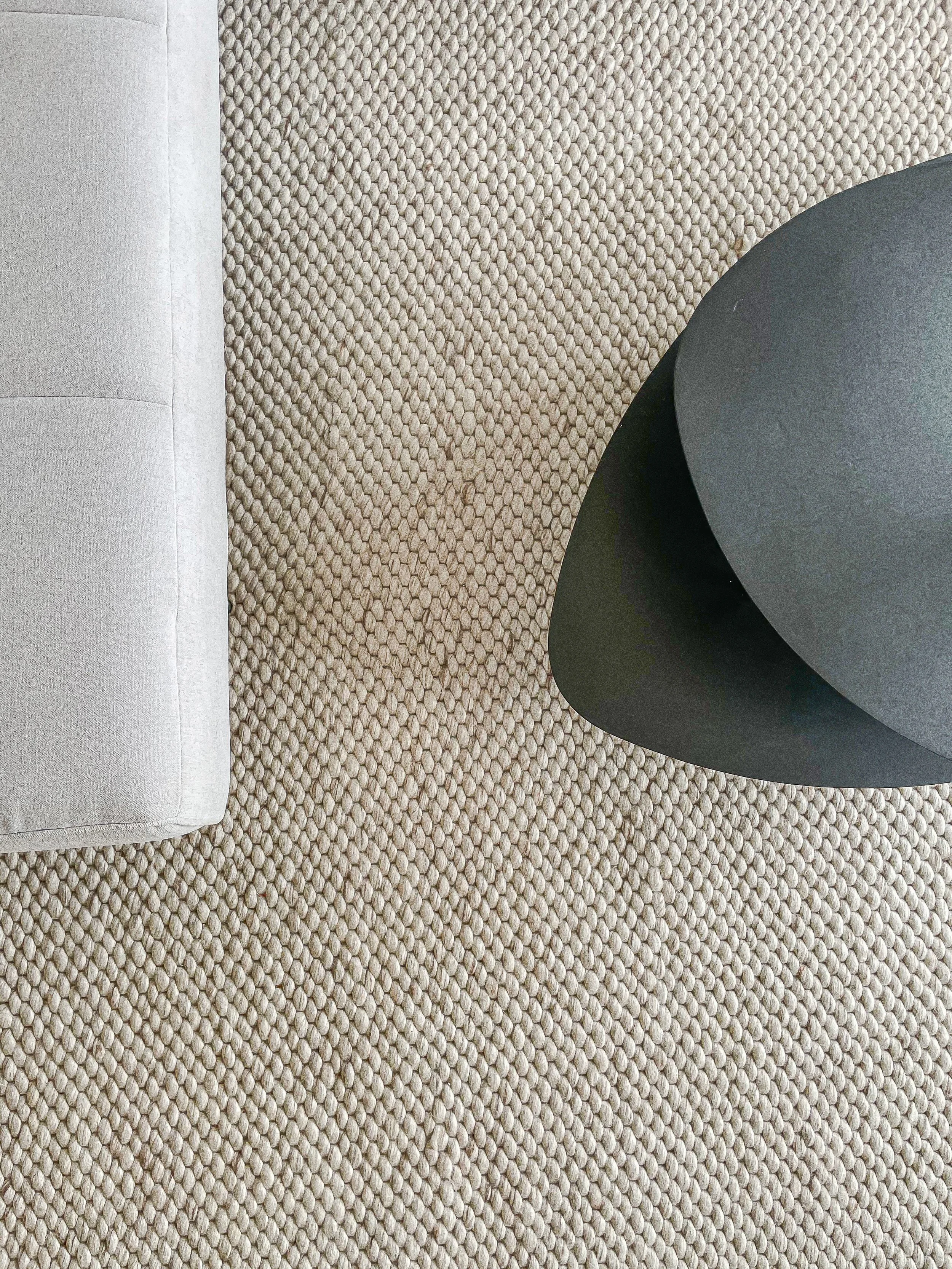 A close-up view of a beige carpeted floor with a partial view of a light gray upholstered piece of furniture and a dark rounded piece of furniture.“Residential interior design project in Scotland by [Studio Name], working across Glasgow, Edinburgh, D