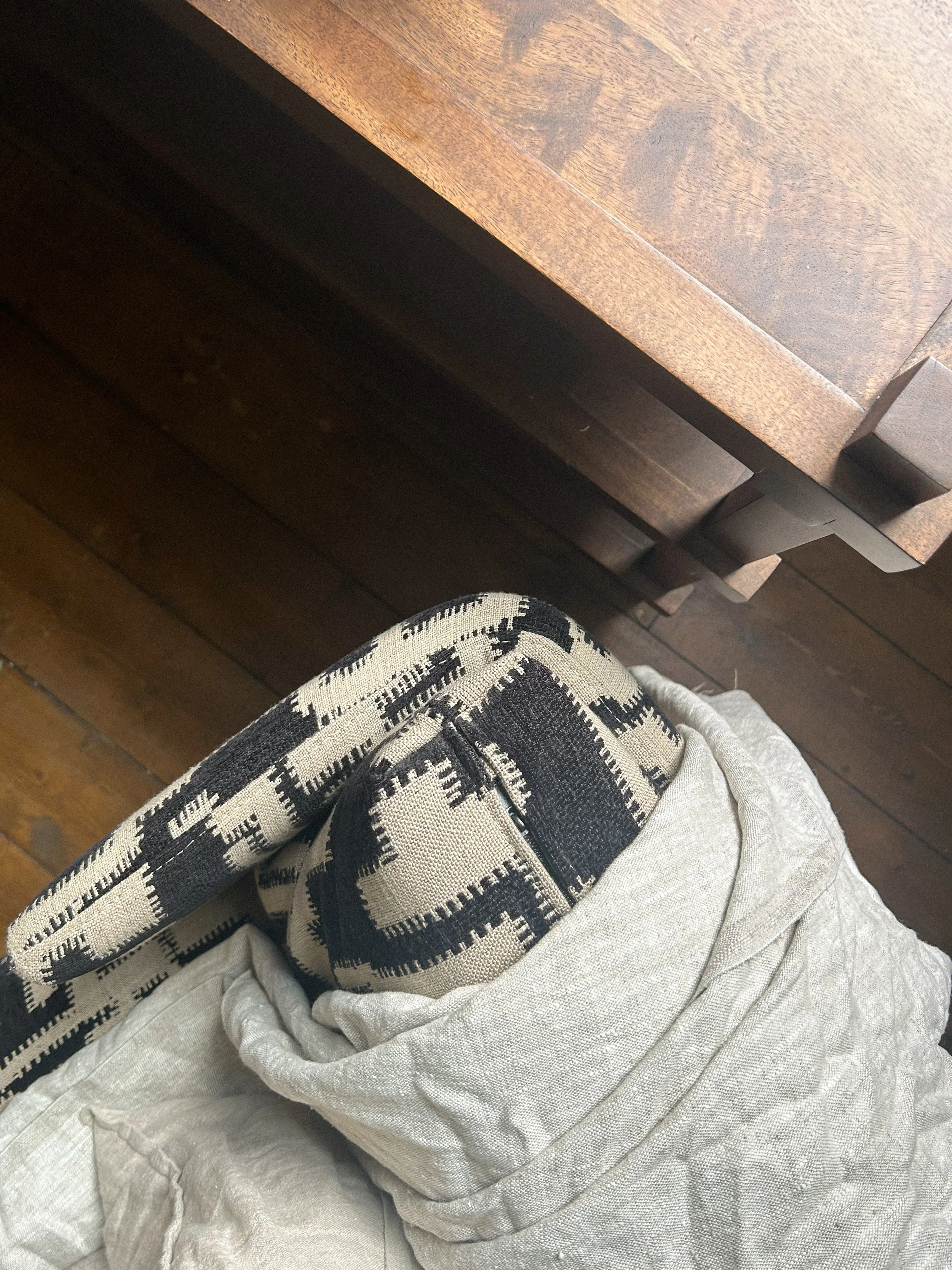 A top-down view of a person's lap, showing beige or light-colored pants, a black and beige patterned scarf, and part of a brown wooden table with a drawer underneath.Residential interior design project in Scotland - Interior Designer Scotland - Inter