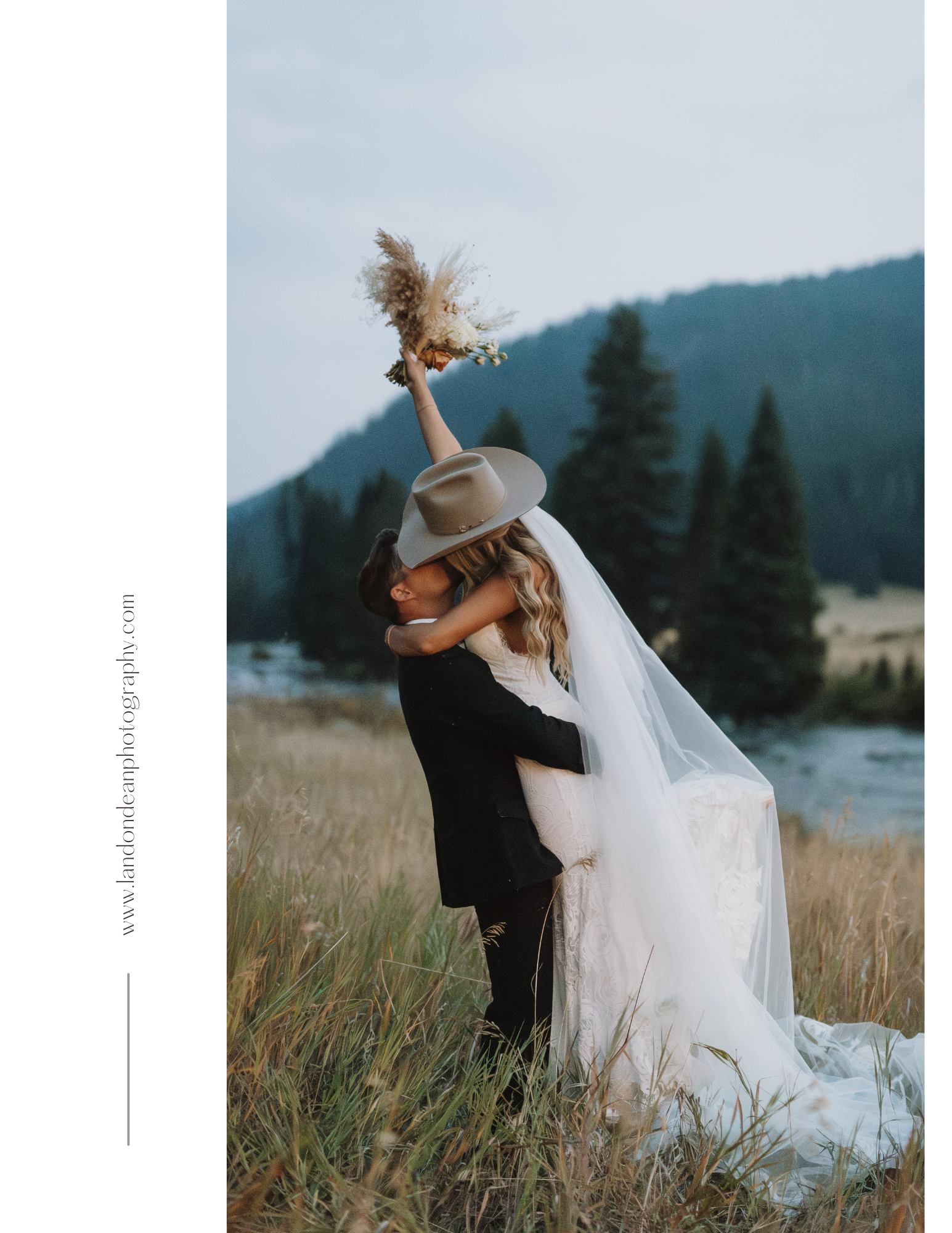A bride and groom embrace and kiss in a grassy field with trees in the background. The bride wears a long dress and veil, holding a bouquet aloft, while the groom wears a suit and hat at 320 Guest Ranch in Big Sky Montana.
