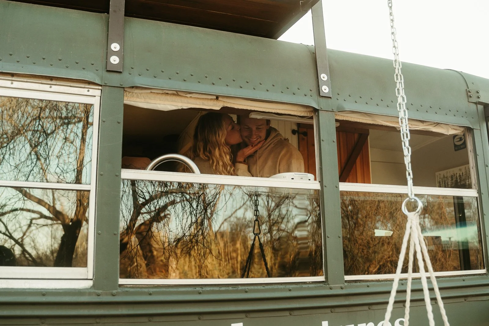 Nikki holding Sawyer's smiling face as she kisses him on the cheek, visible from a bus window.