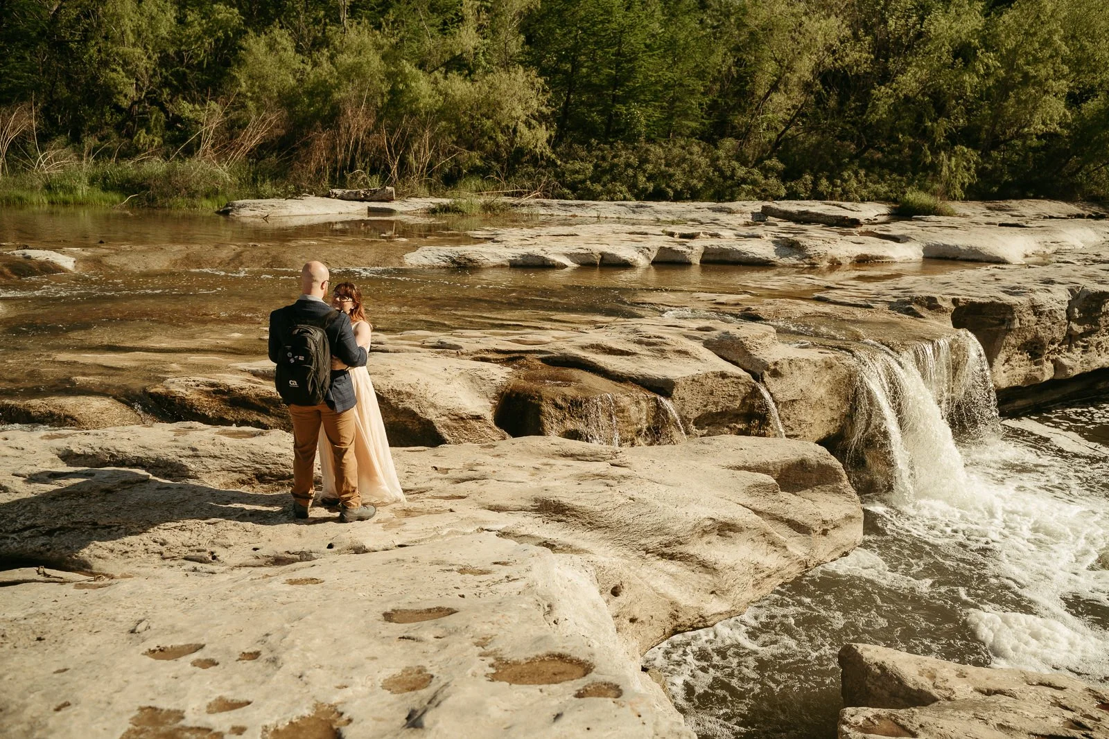 couple holding each other on a limestone cliff next to the lower falls at McKinney Falls State Park