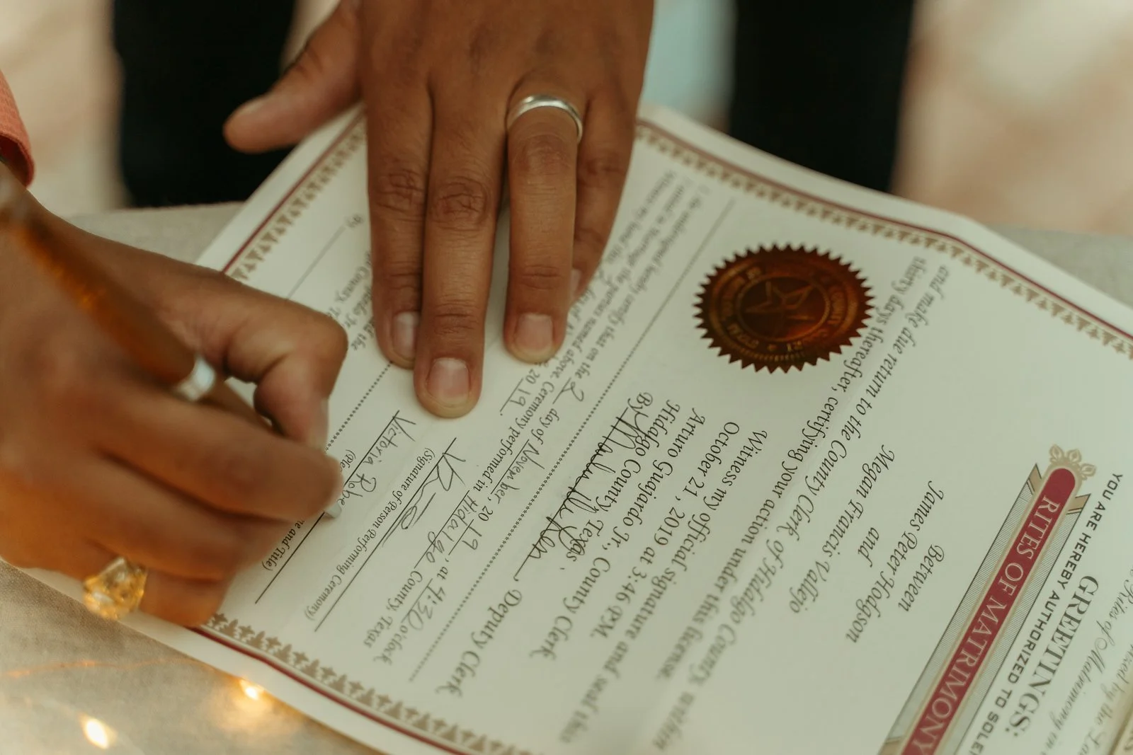 officiant’s hands as they sign a marriage license