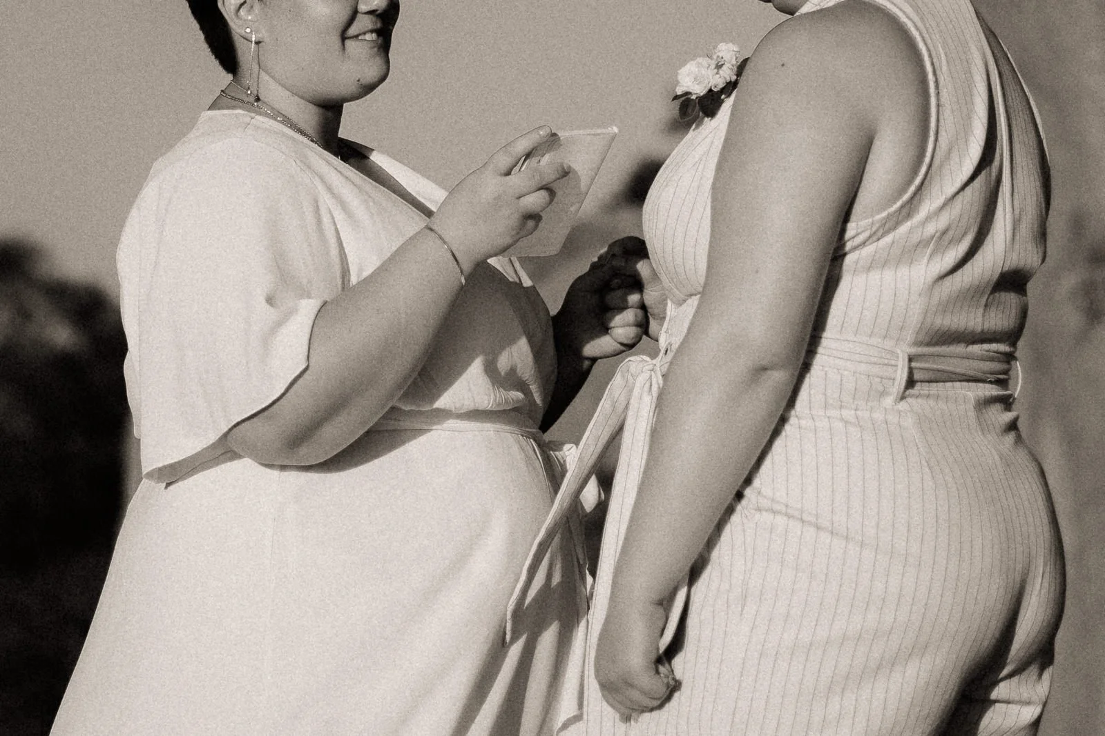 bride holding her partner’s hand and smiling while reading her vows during the ceremony