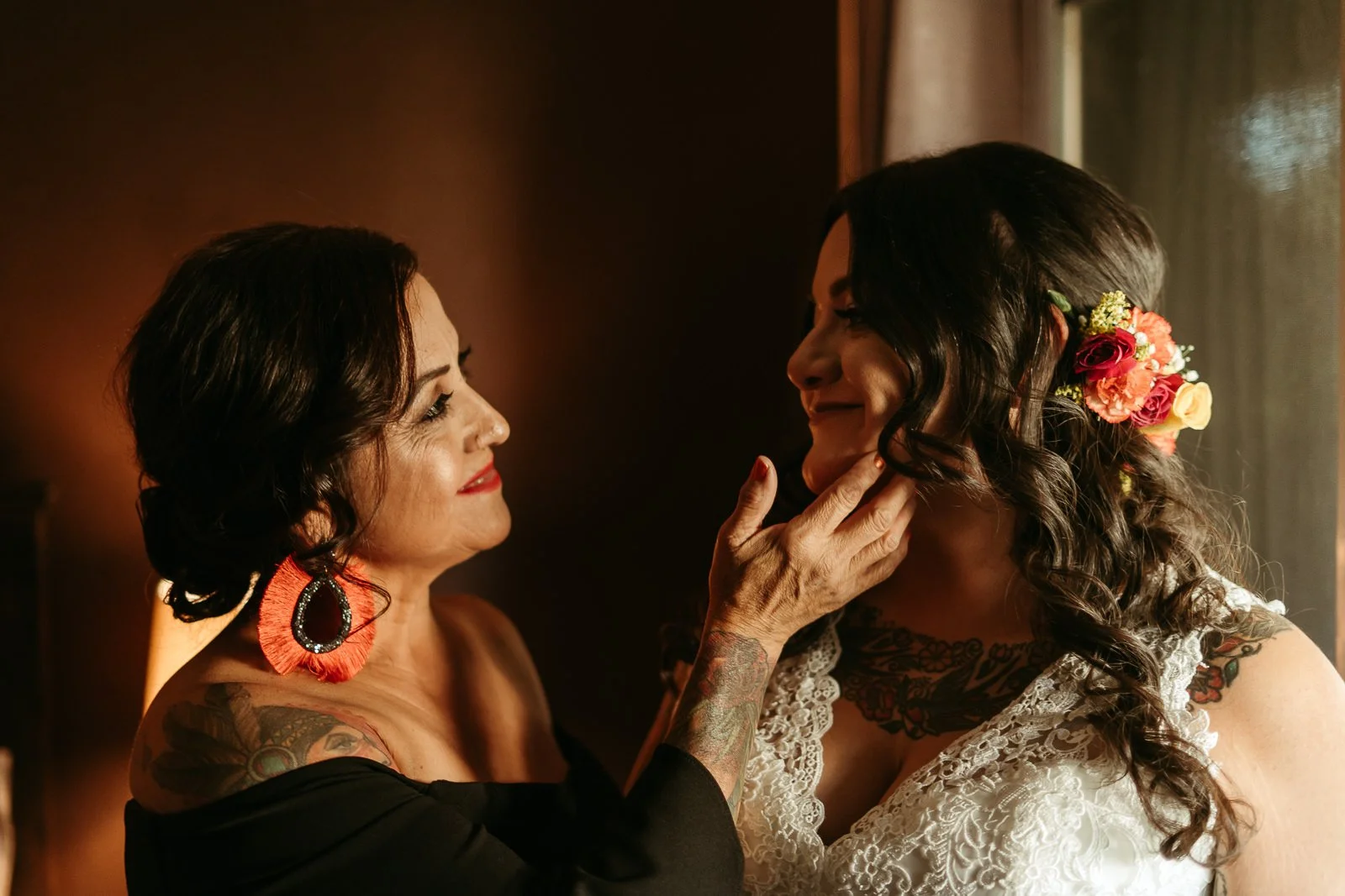 A smiling mother places her hand on her daughter’s cheek as she prepares for the wedding ceremony.