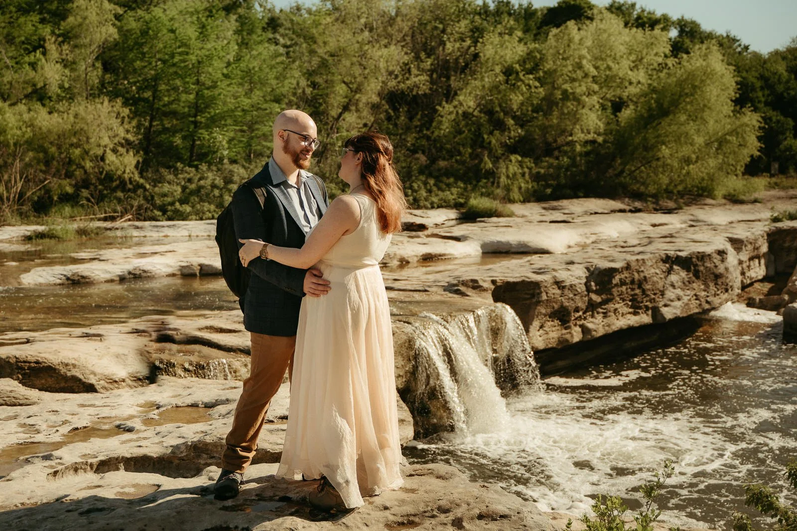 couple holding each other on a limestone cliff next to the lower falls at McKinney Falls State Park