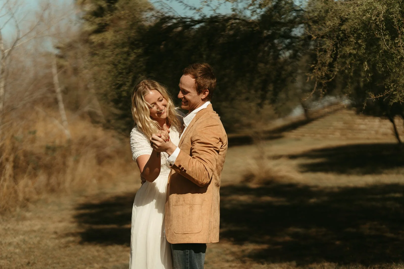 Nikki and Sawyer smile as they dance in a grassy picnic area after their ceremony together.