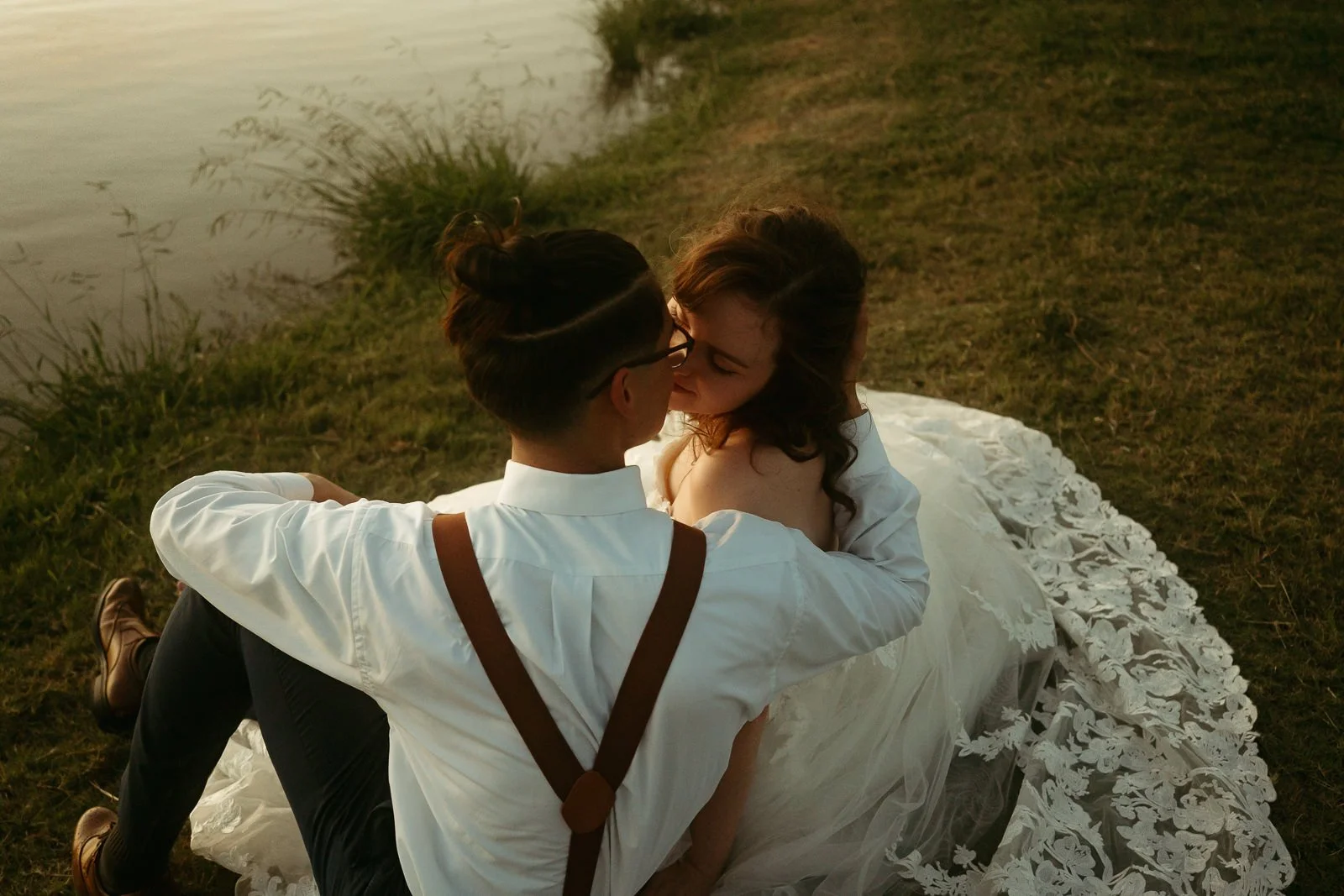 couple sitting on a lake shoreline at dusk