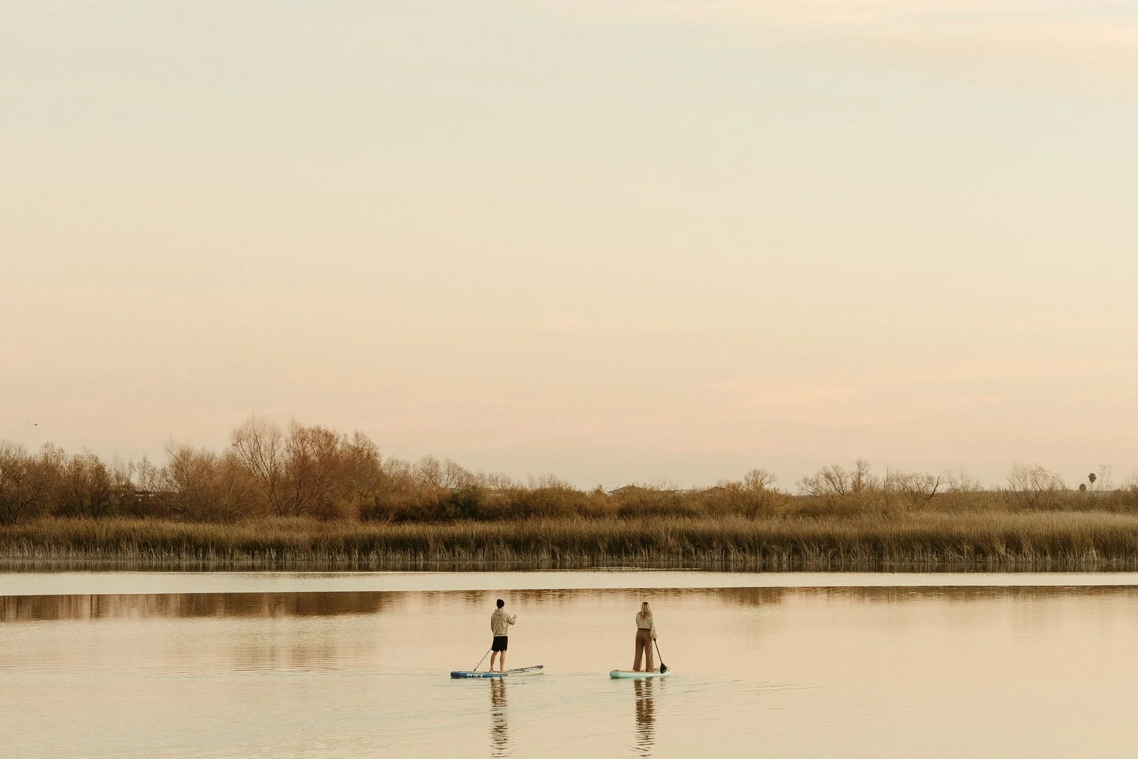 couple paddle boarding on Tyler Lake at sunrise