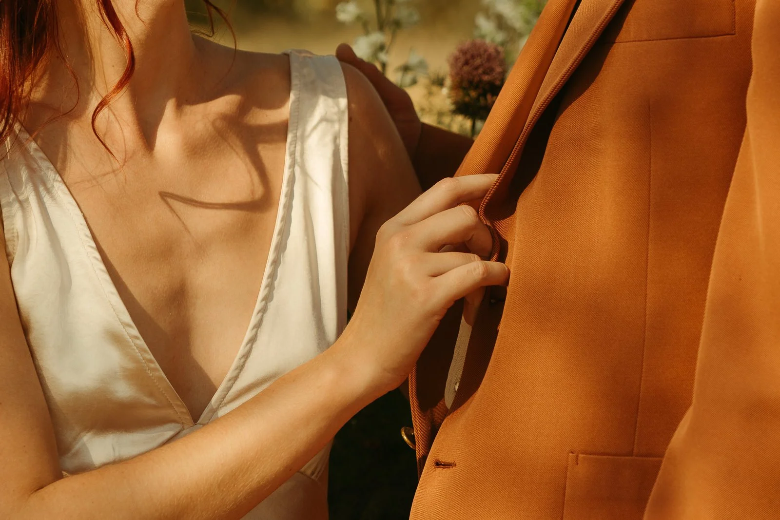 a bride’s hand holding on the groom’s jacket as they kiss