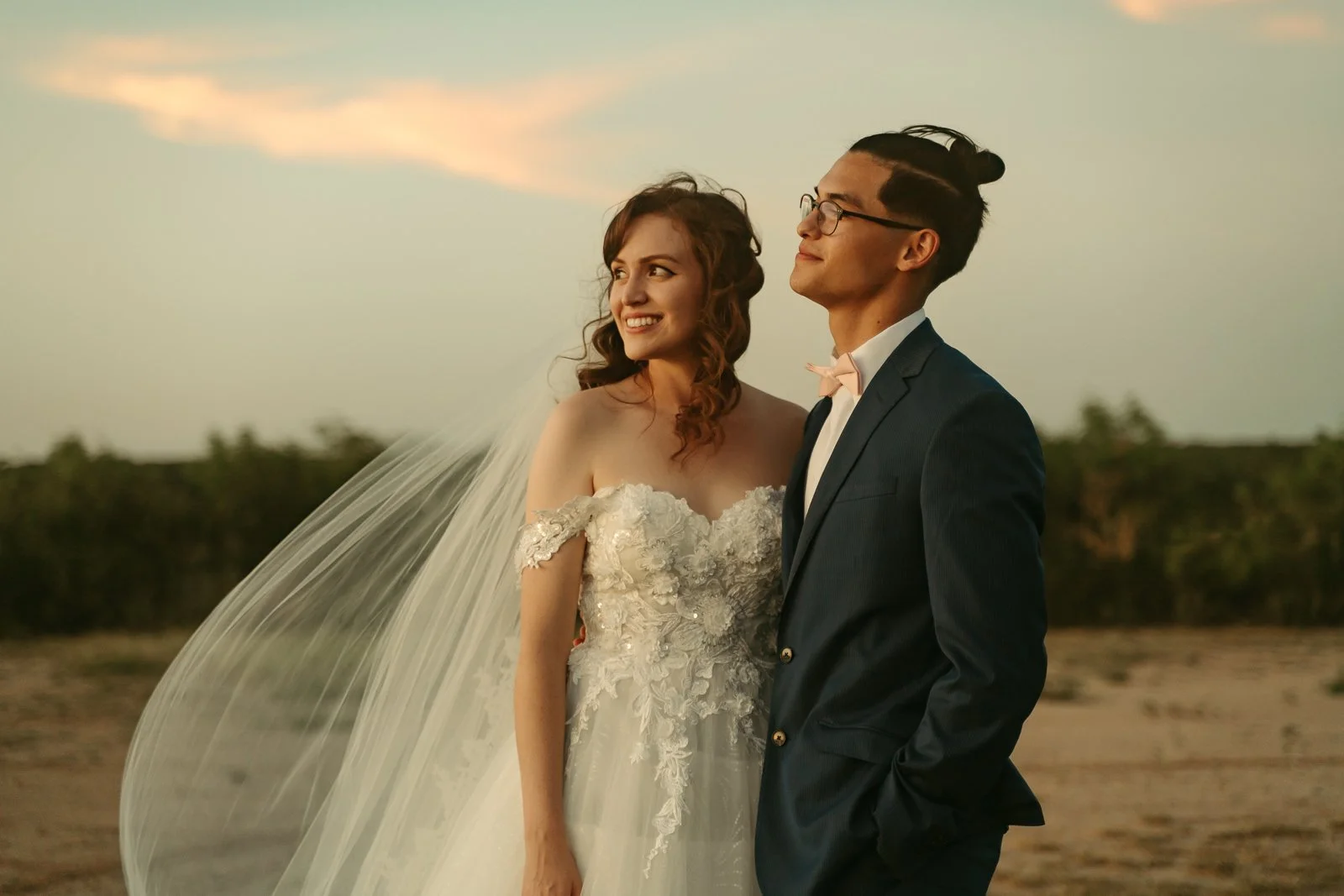 bride and groom smiling as they watch the sunset together