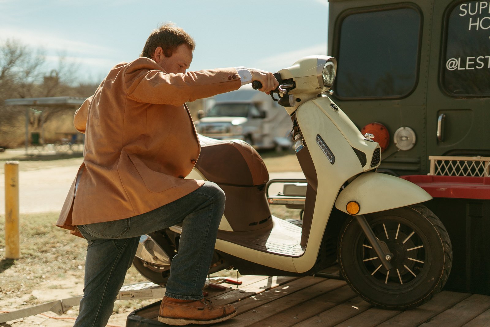 Sawyer rolling their Vespa back onto the back of their skoolie.