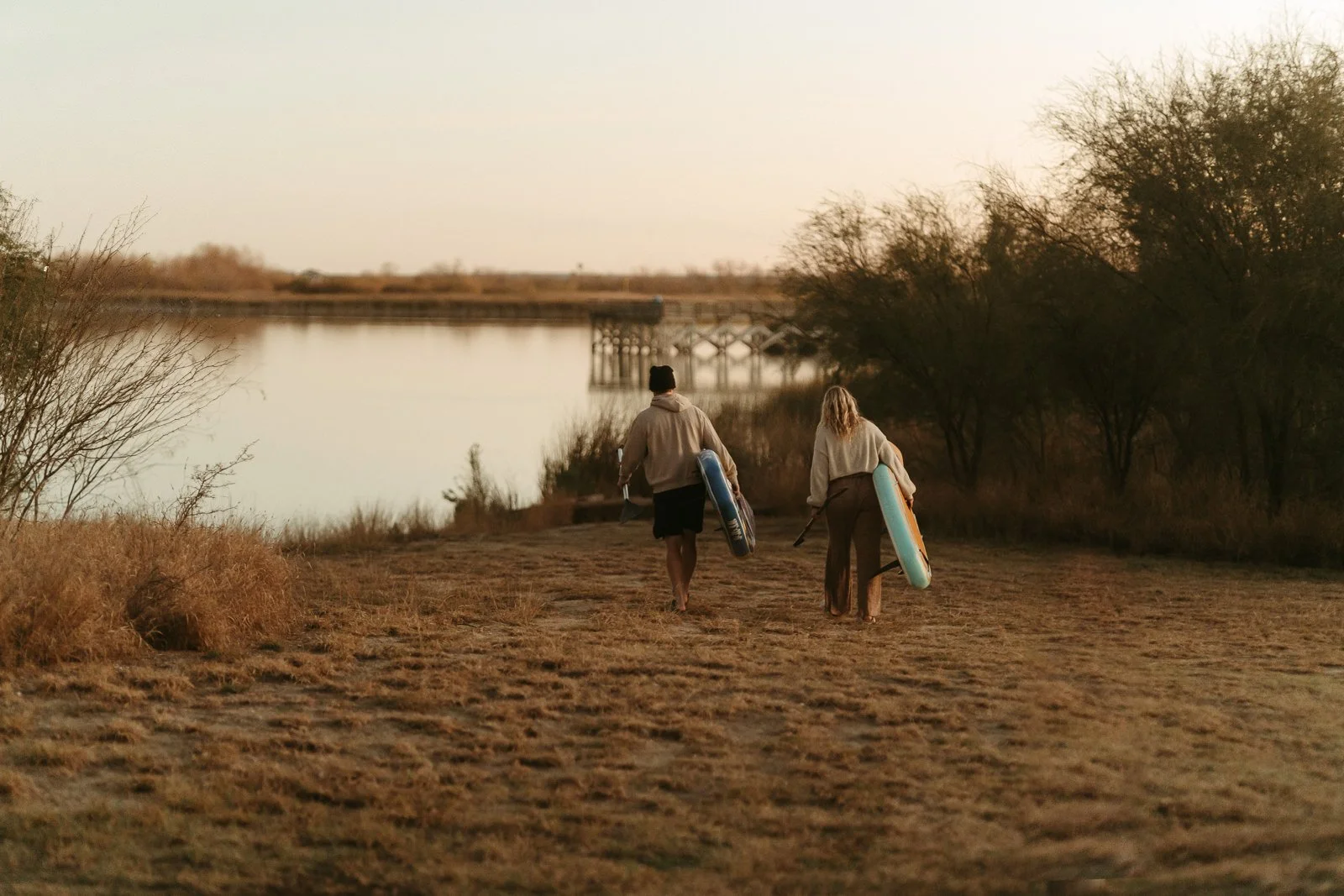 Sawyer and Nikki carrying their paddleboards down to the Lake Casa Blanca lakeshore.
