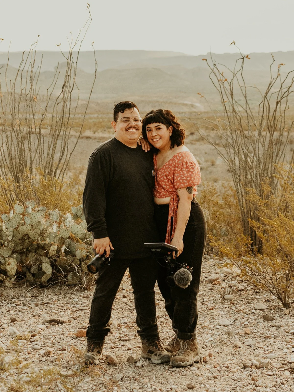 Kevin and Nora elopement photographer and videographer duo standing in the West Texas desert while holding their cameras