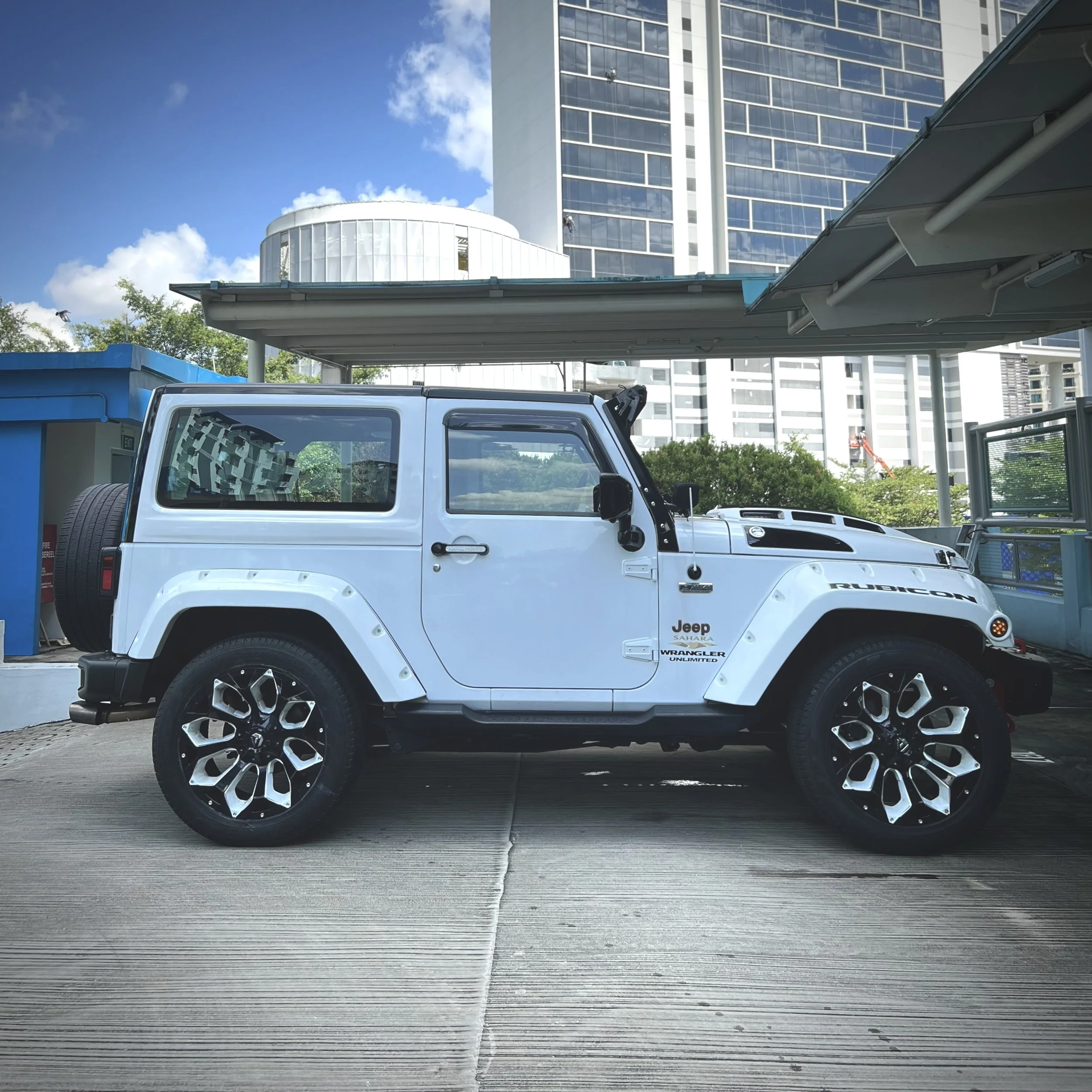 White Jeep Wrangler Rubicon parked outdoors with tall building in background