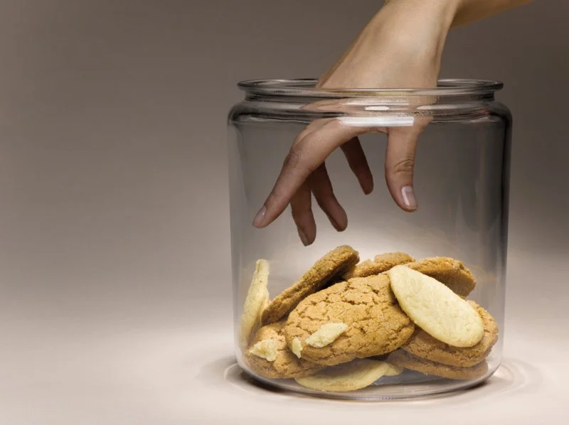 Hand reaching into a cookie jar, a concept of snack temptation, for an Ebylife article on healthy eating