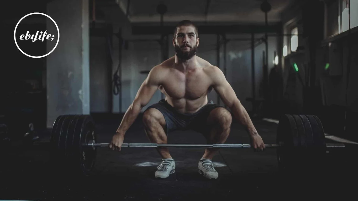 Man preparing to deadlift a heavily loaded barbell in a gym