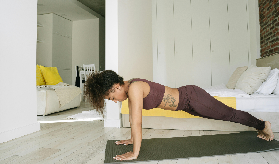Woman performing a bodyweight plank exercise in a hotel room during a travel workout