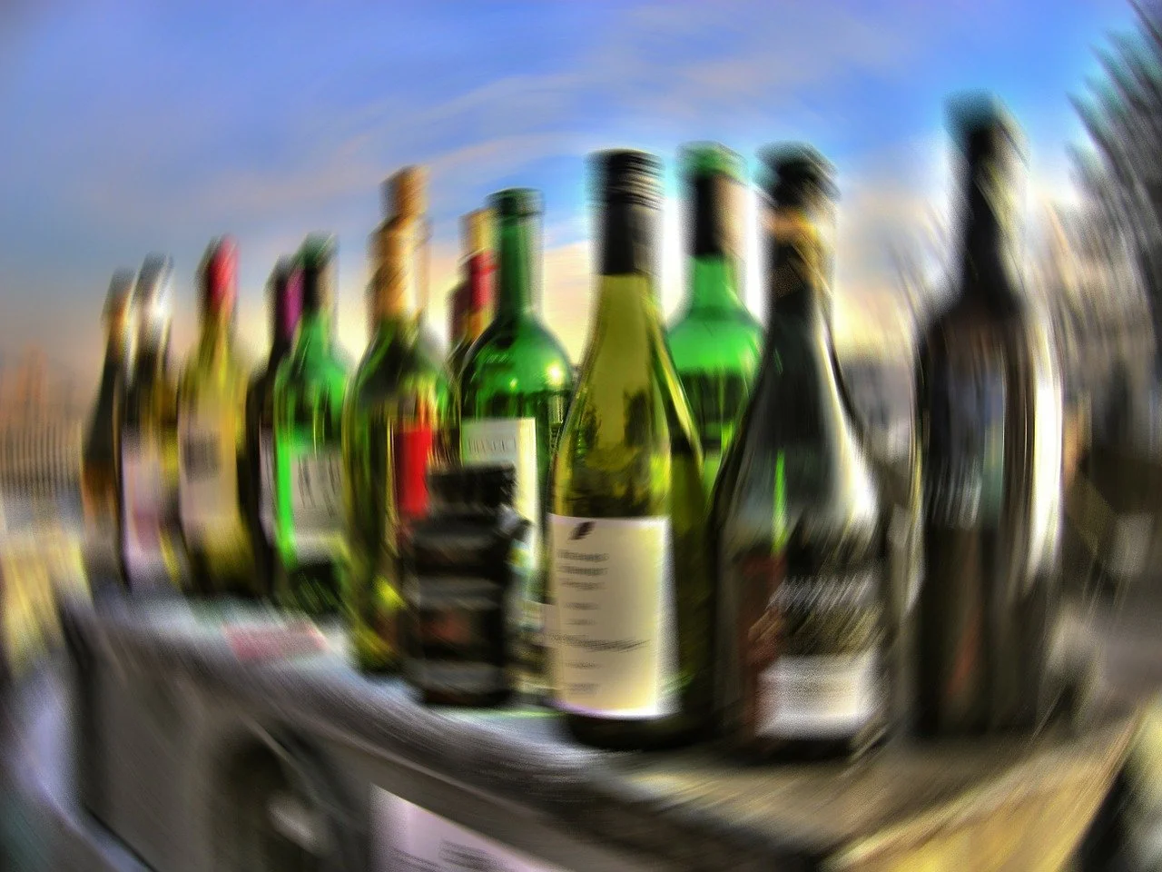 Blurred assortment of wine bottles, representing the challenge of alcohol moderation for diet maintenance on the weekend