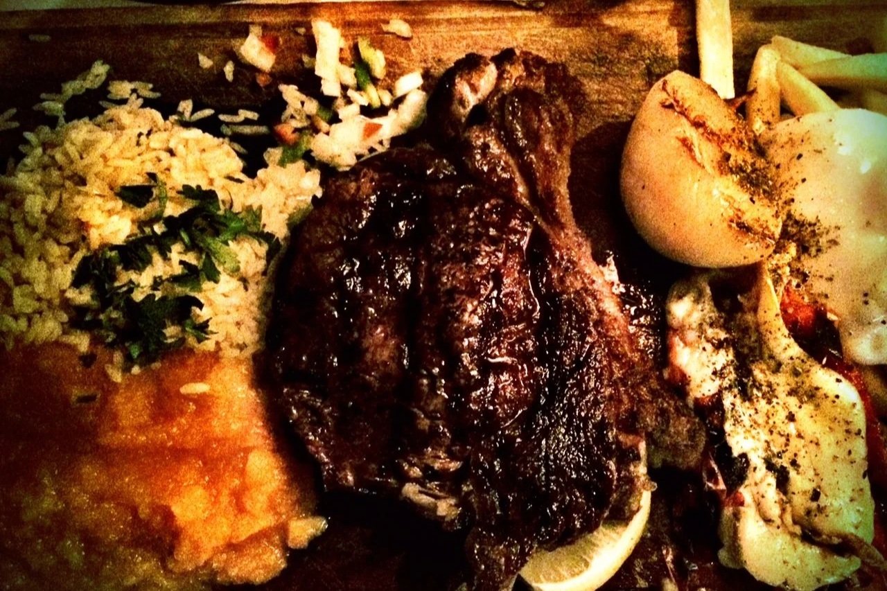 Plate of grilled beef, provoleta and side dishes at an Argentine asado