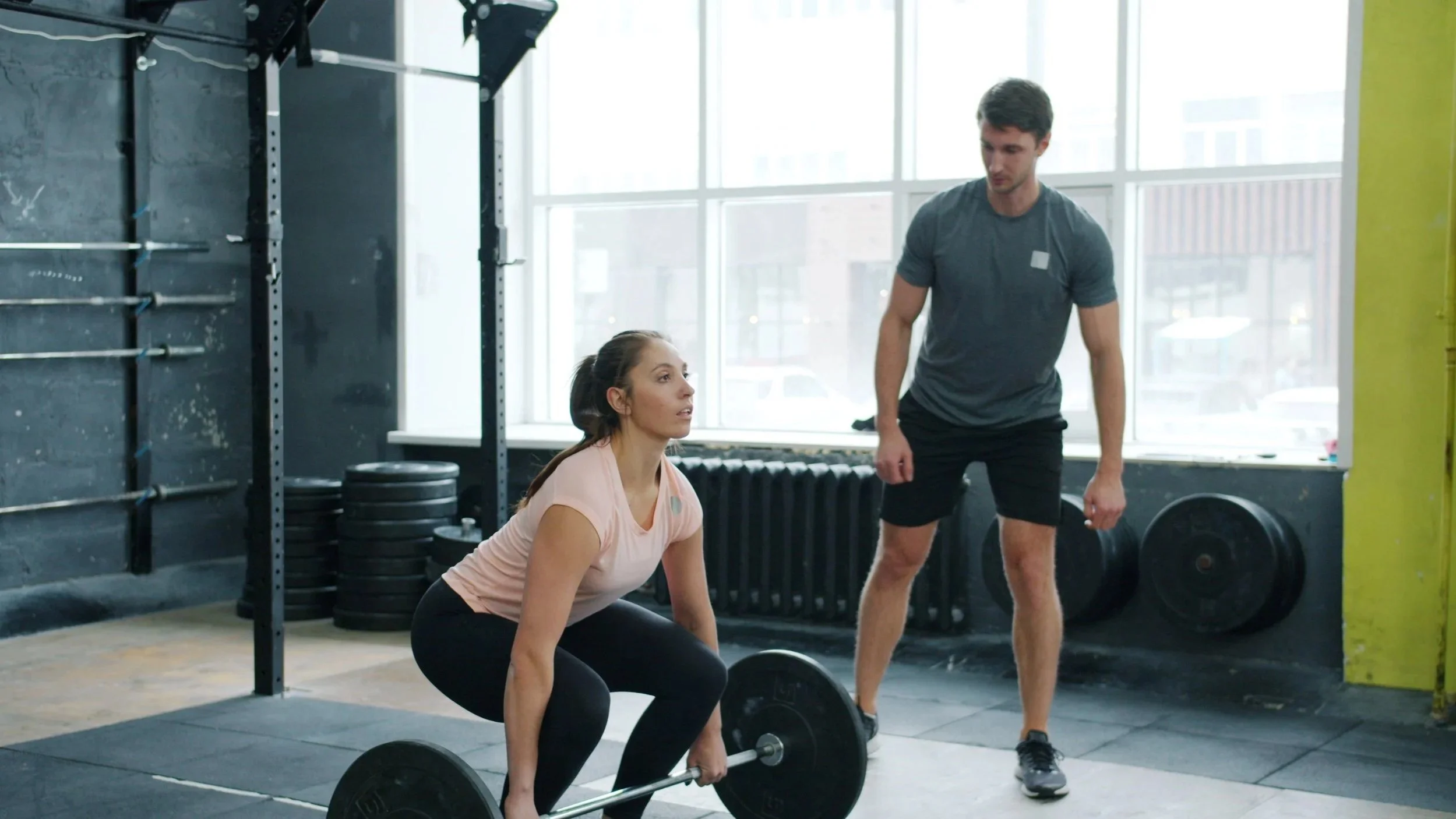 Personal training spotting a client doing a deadlift